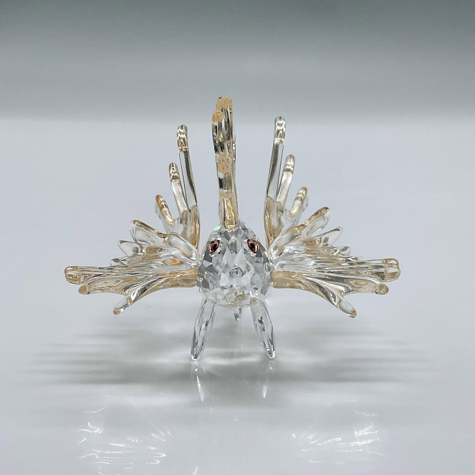 Swarovski Crystal Figurine, Lion Fish: This spectacular figure is made from clear crystal with light amber colored fins and salmon colored eyes. This item has its original box measuring 4"H x 4.75" dia. Swarovski acid mark. 604011. Artist: