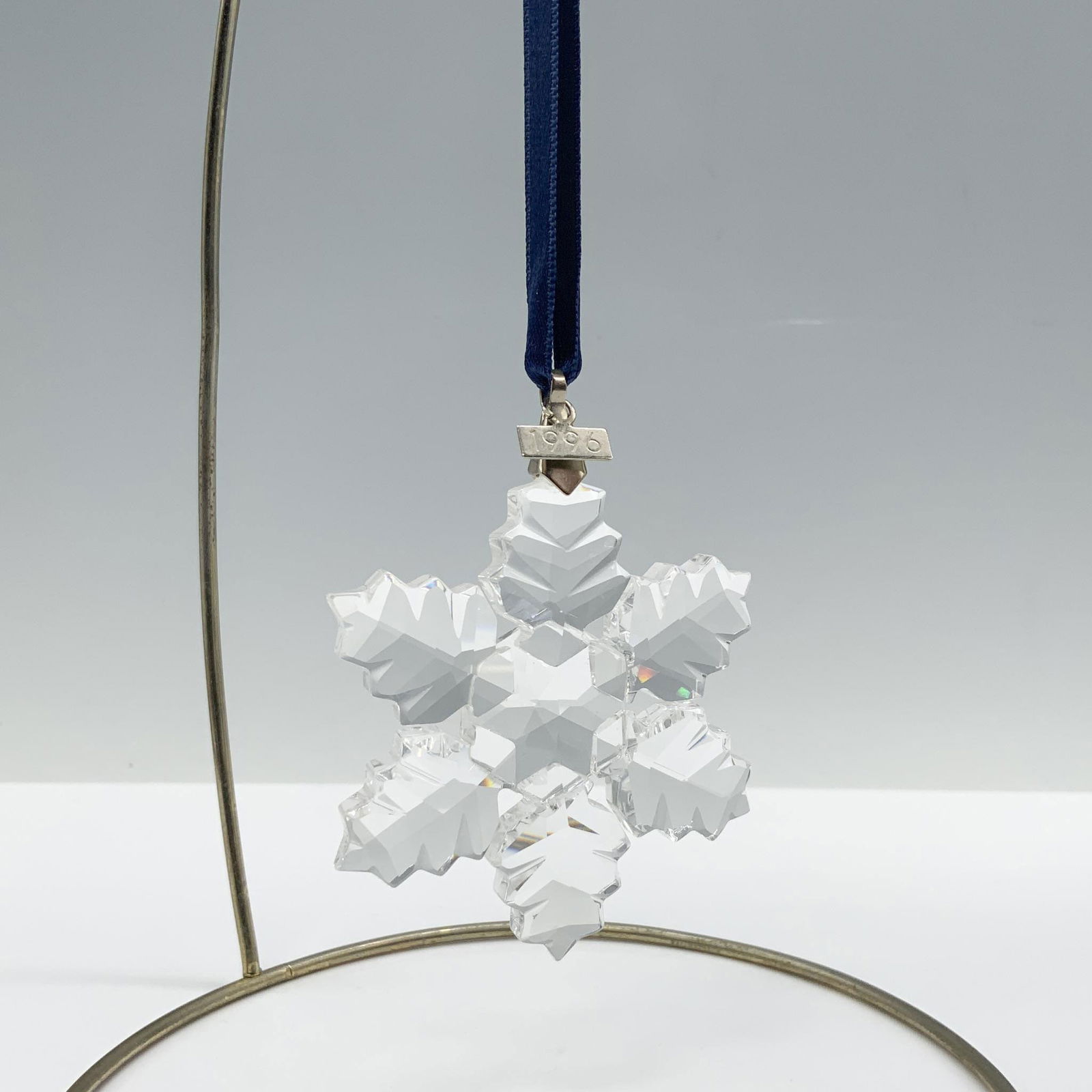Swarovski Crystal 1996 Christmas Ornament: Limited edition Swarovski Christmas ornament with 6 points in the shape of leaves and a metal tag with 1996 etched on it. Hung by a blue ribbon. 199734. Artist: Martin Zendron Issued: 1996 Dimensions: