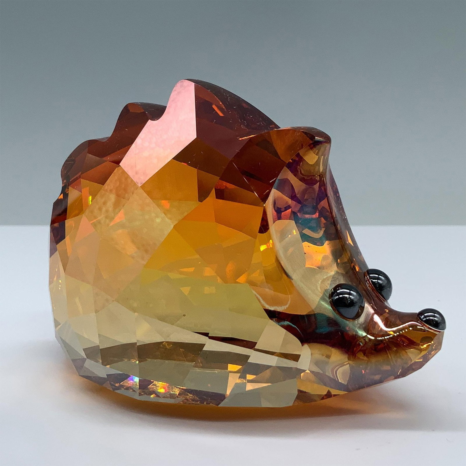 Swarovski Crystal Figurine, Lovlots City Park, Nick: Showcasing a hedgehog in a highly detailed faceted design that reflects a warm amber hue. The figure has black eyes and nose. 1041297. Artist: Anton Hirzinger Issued: 2010-2011 Dimensions: 3.75"L x 2.