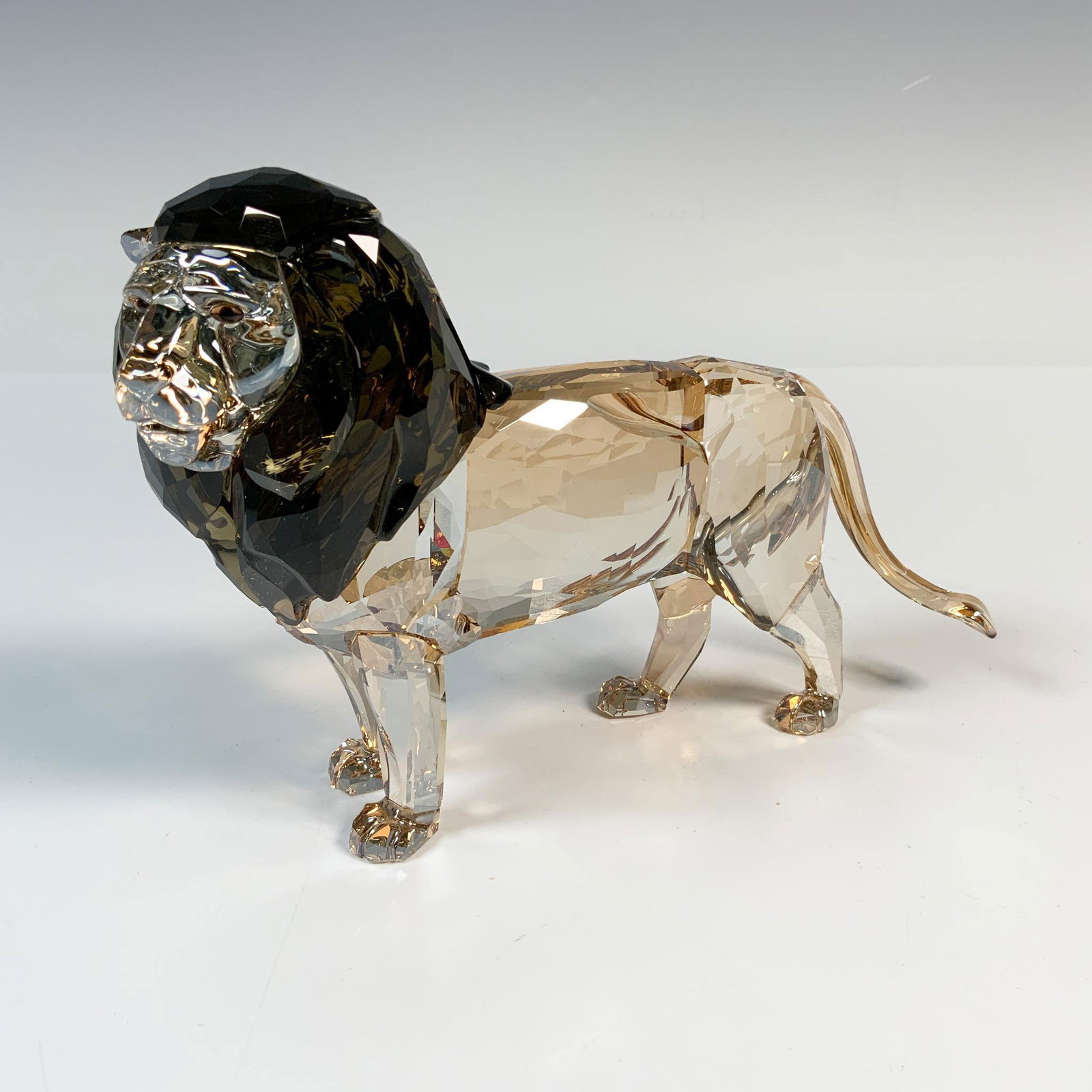 Swarovski Crystal Figurine, Akili Lion: Swarovski crystal figurine SCS Annual Edition 2016 Lion Akili showcases a striking design with a faceted golden crystal body and a contrasting jet black crystal mane. Part of Swarovski's Rare Encounte