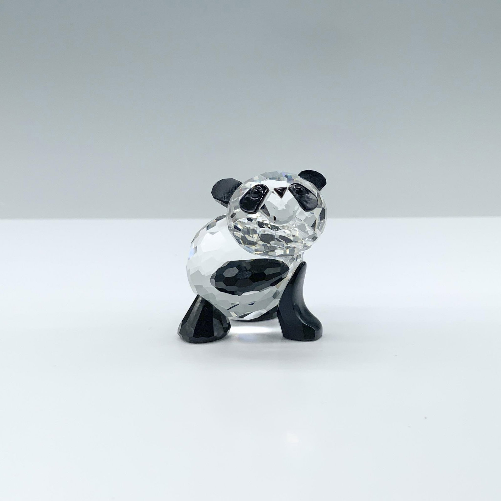 Swarovski Crystal Figurine, Panda Mother: Adorable mini clear faceted crystal figure with jet crystal ears, paws and eyes. Swarovski backstamp. 181080. Artist: Adi Stocker Issued: 1994-2006 Dimensions: 1.5"L x 1.5"W x 1.5"H Manufacturer: Swar