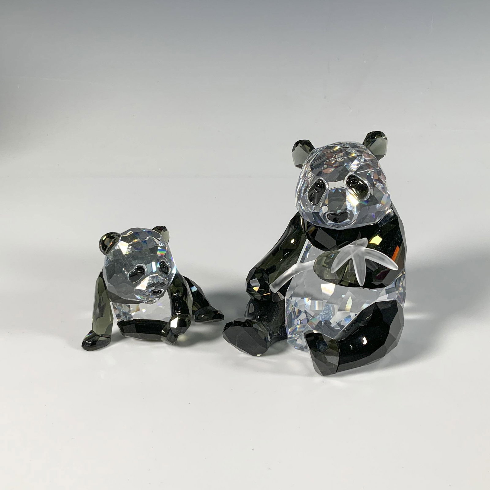 Swarovski Crystal Figurines, Panda Mother & Cub: An exquisite duo of faceted figures, depicting a panda mother holding a frosted bamboo, accompanied by her cub. Part of the Endangered Wildlife trilogy. This item has its original box: 8.75"L x 8.75"W