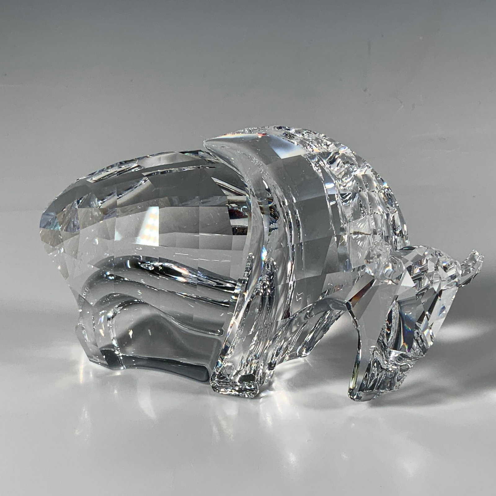 Swarovski Crystal Figurine, Symbols Buffalo: An impressive cut crystal figure depicting a buffalo, featuring smooth inward curves along its legs. Swarovski acid mark. Artist: Martin Zendron Issued: 2003-2005 Dimensions: 6.5"L x 2.5"W x 3.75"H Ma