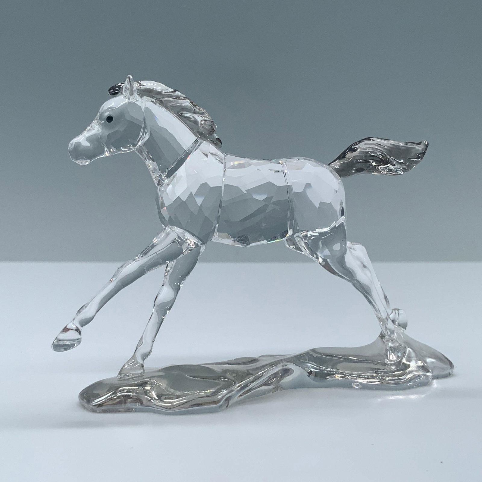 Swarovski Crystal Society Figurine, Foal Horse: Features a faceted horse in a prancing posture. The mane, tail, and a flowing base simulates movement. Part of the 2014 annual edition for the SCS. Swarovski swan backstamp. This item has its original