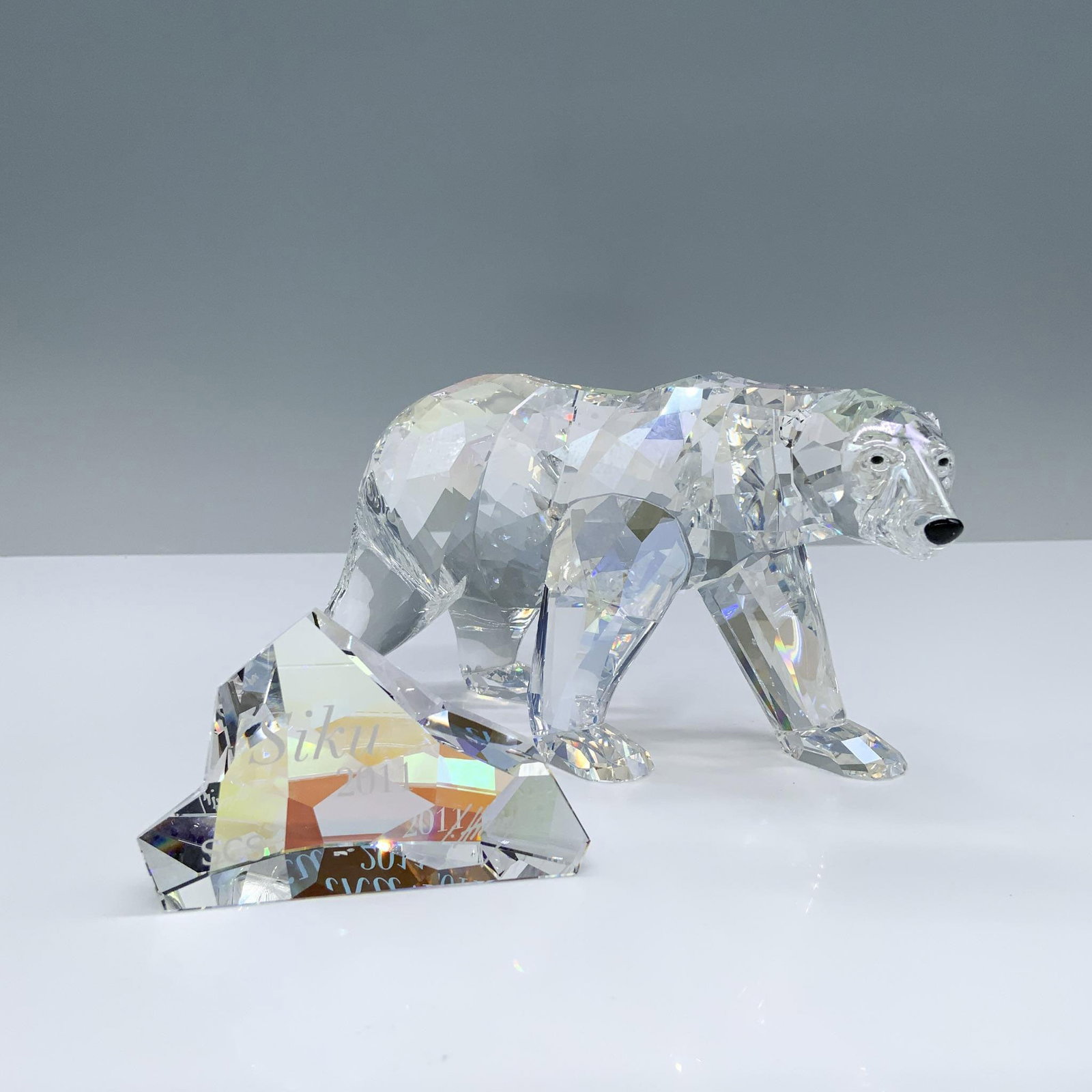 Swarovski Crystal Society Figurine + Plaque, Siku Polar Bear: A 2011 annual edition of an Artic bear in moonlight colored crystal with black crystal eyes and nose. Includes an iceberg formed plaque in aurora borealis crystal; Siku 2011, SCS, and artist name engr