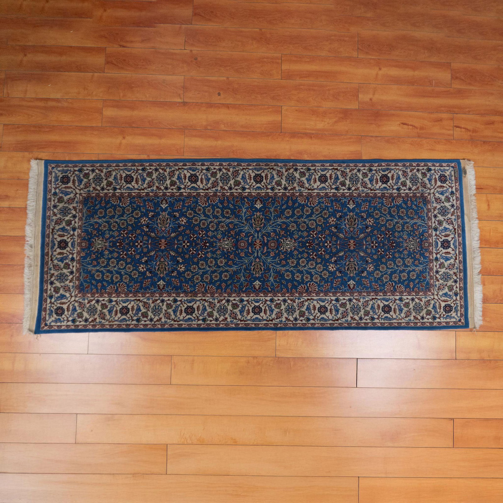 Yuksel Halicilik & Han Hereke Blue Floral Rug: A lovely long blue rug with a delicate white border, adorned with an elegant pattern of spring flowers gracefully weaving together in a harmonious design. Han Hereke manufacturing badge. Yuksel Halici