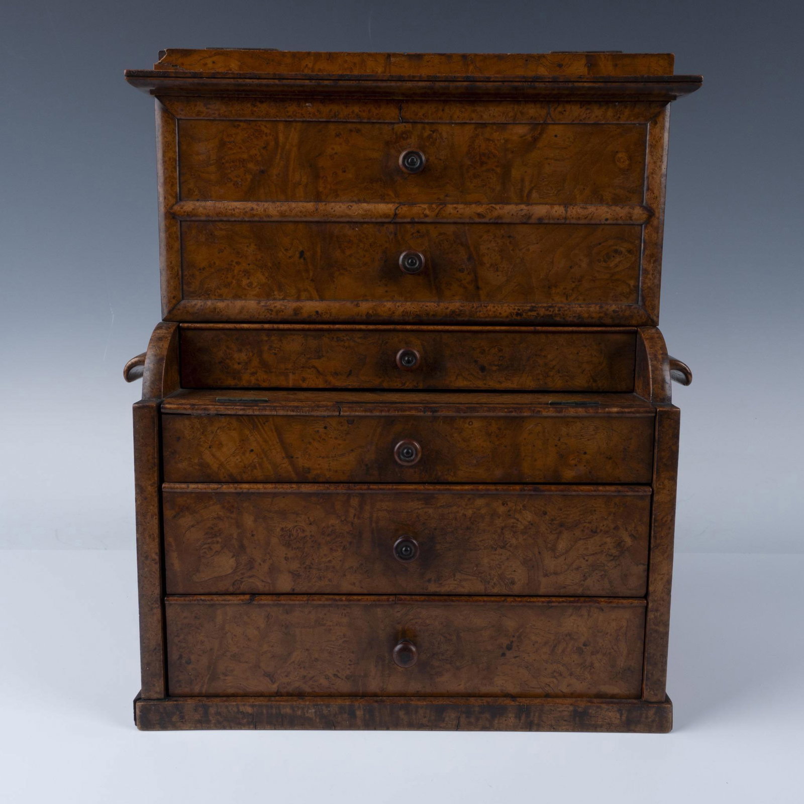 Victorian Miniature Wood Stationary Cabinet with Drawers: Beautifully crafted cabinet features a burl wood veneer finish. The top lifts to reveal a series of narrow, organized shelves designed for storing documents. Below the shelves are three drawers with d