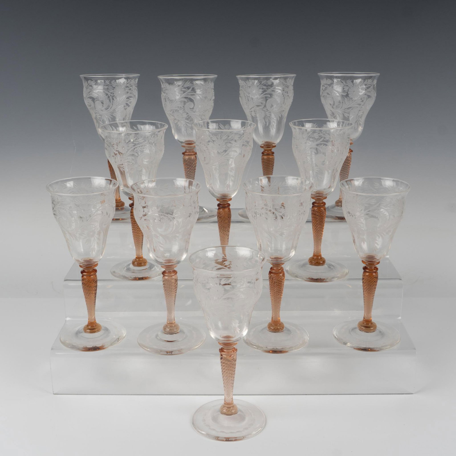 12pc Steuben Crystal Van Dyke Claret Wine Glasses: A twelve-piece set of refined crystal glassware, featuring detailed etched floral patterns and rosa-colored twist-patterned stems. Steuben acid mark. Dimensions: 7"H x 3"dia. Manufacturer: Steuben Cou