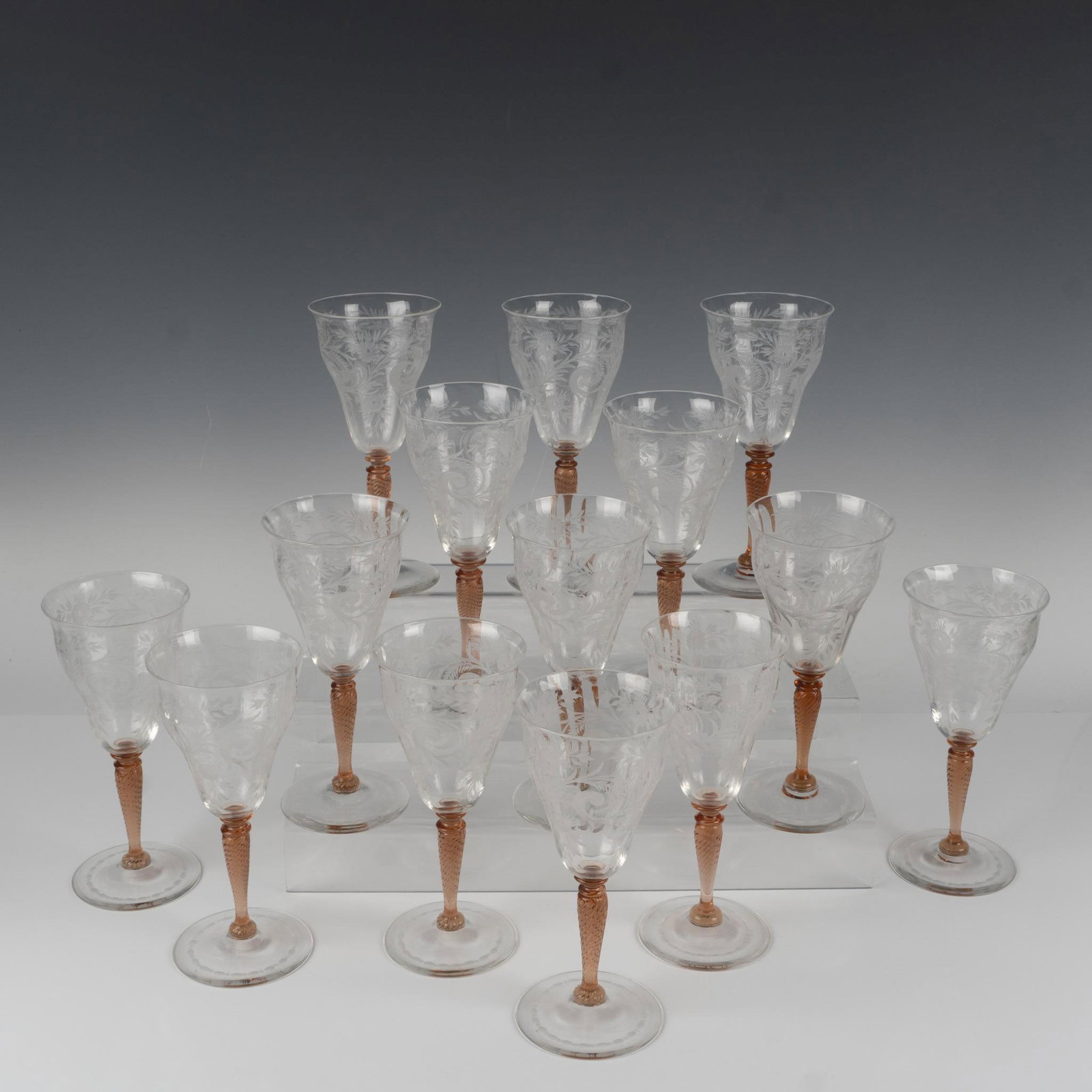 14pc Steuben Crystal Van Dyke Wine Glasses: A marvelous fourteen-piece collection of sophisticated glassware, featuring detailed etched floral designs and rosa-colored swirl-patterned stems. Steuben acid mark. Dimensions: 8.25"H x 3.75" dia. Ma