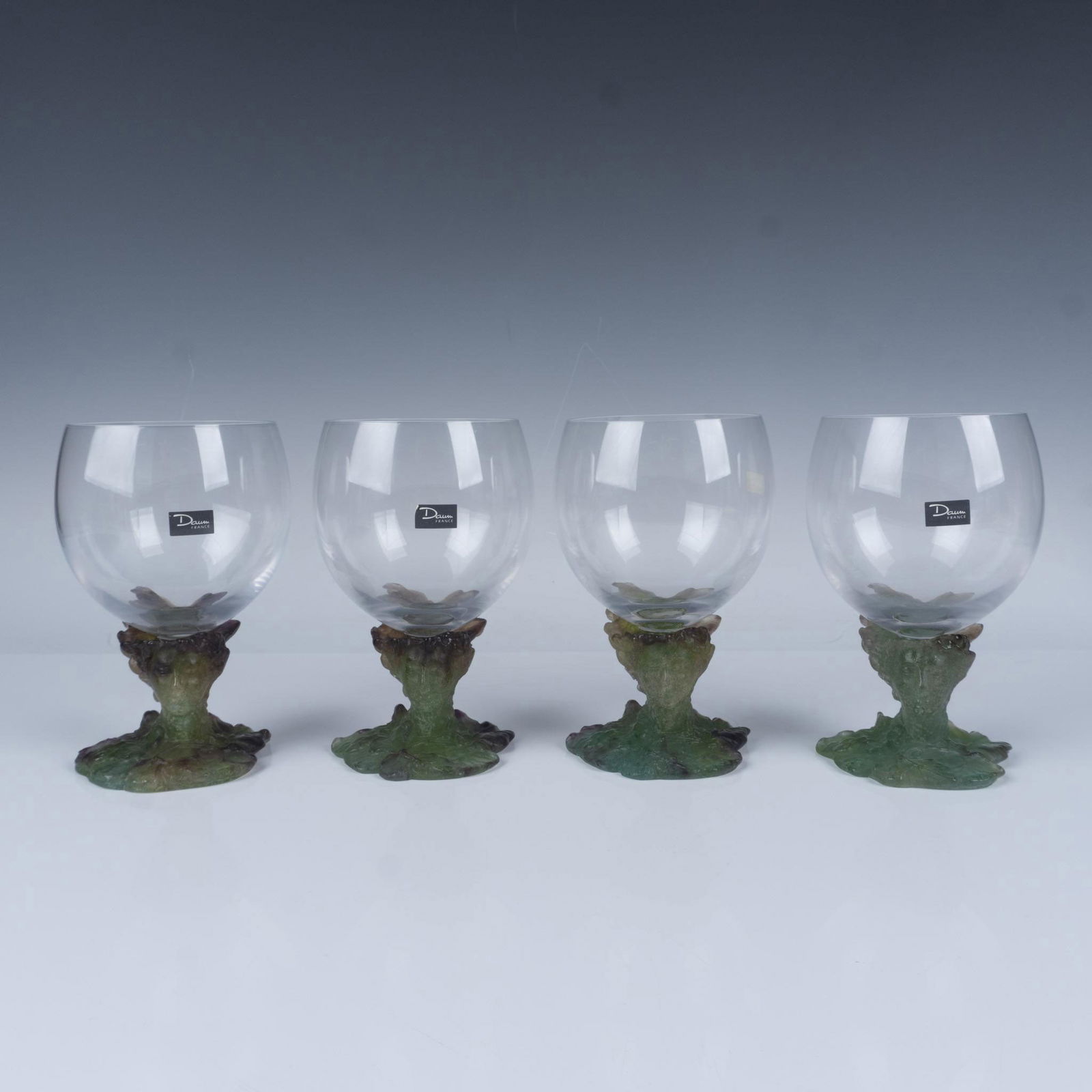 4pc Set of Daum Pate de Verre Bacchus Snifters Glasses: Gorgeous set of 4 clear glasses perched atop sculptural bases crafted from Pate de Verre, featuring the Roman god of wine surrounded by grapevine motifs in vibrant green and earthy tones, symbolizing