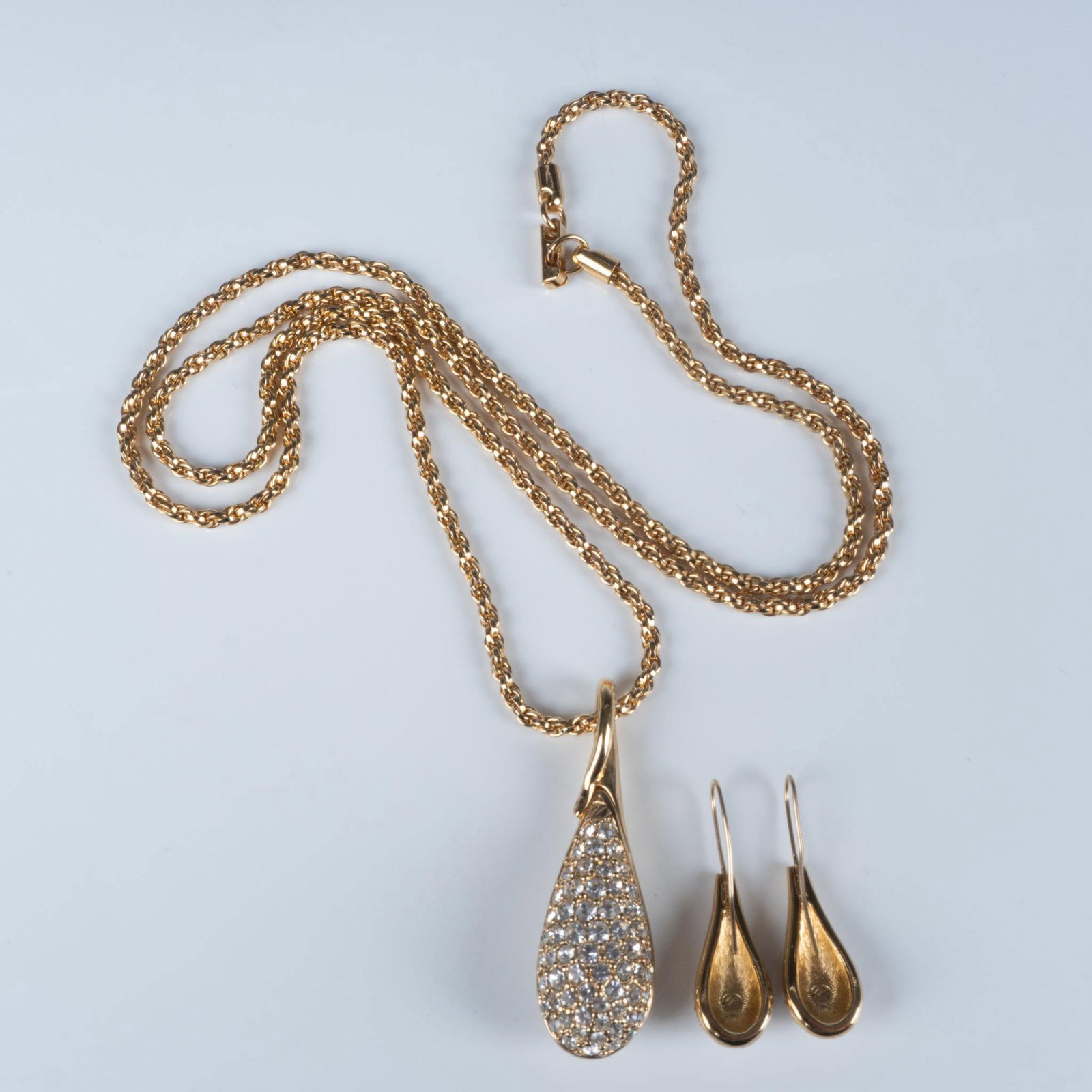 2pc Swarovski Crystal Gold Teardrop Necklace & Earrings: A sophisticated gold-toned duo featuring radiant clear crystals, consisting of a long rope chain necklace with a teardrop-shaped pendant, complemented by a pair of coordinating hook earrings. Swarovsk