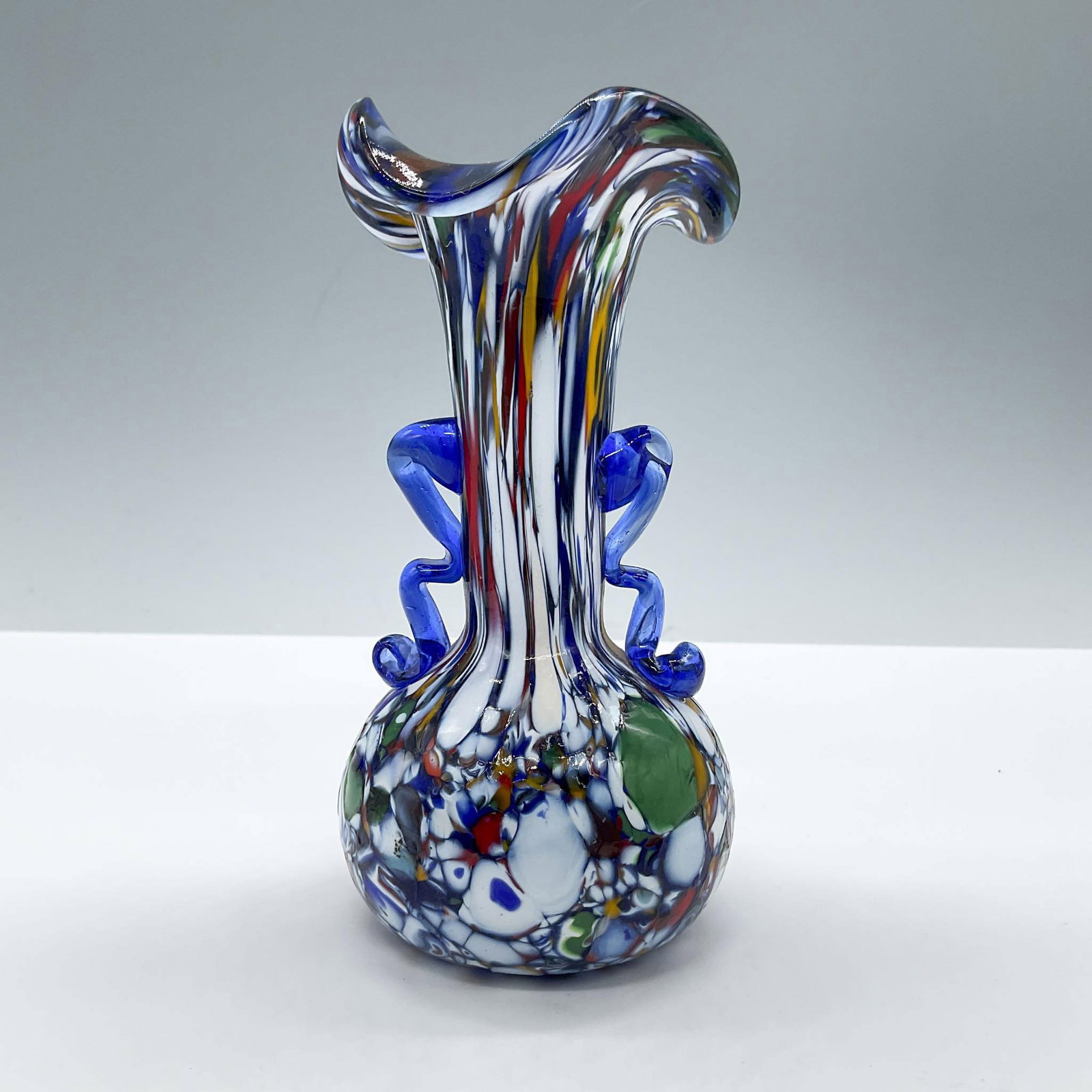 Murano Style Art Glass Vase, Carnivale: In the style of Murano art glass for the celebration of the Carnivale festival in Venice. Features a small bud vase mouth blown in a dark blue core covered with a variety of multicolored spots. Issued