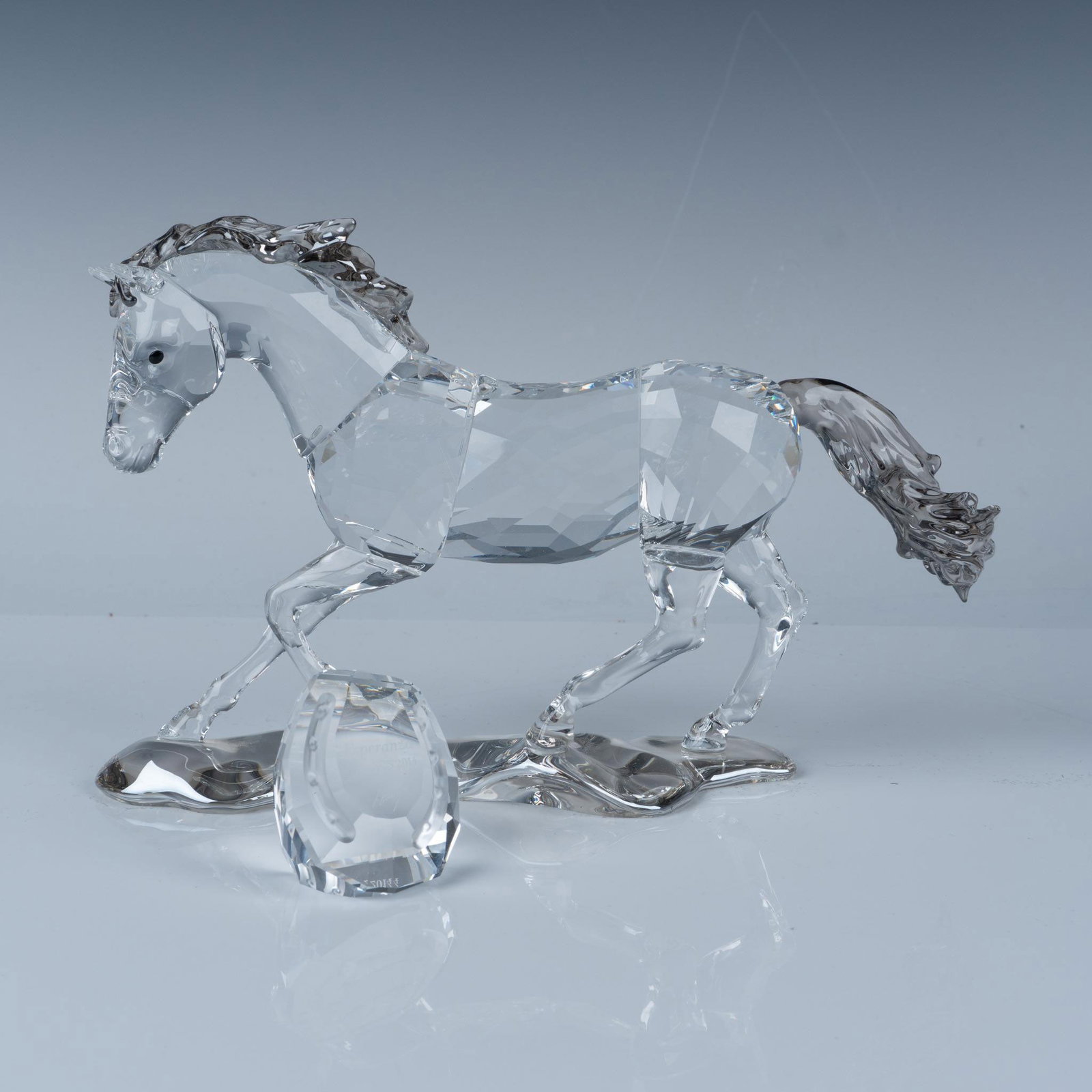 Swarovski Crystal 2014 SCS Figurine + Plaque, Esperanza: This stunning figure, inspired by the wild Criollo horses of South America, features a clear body with a soft, gray-hued mane and tail. It is accompanied by a horseshoe shaped faceted crystal plaque. 