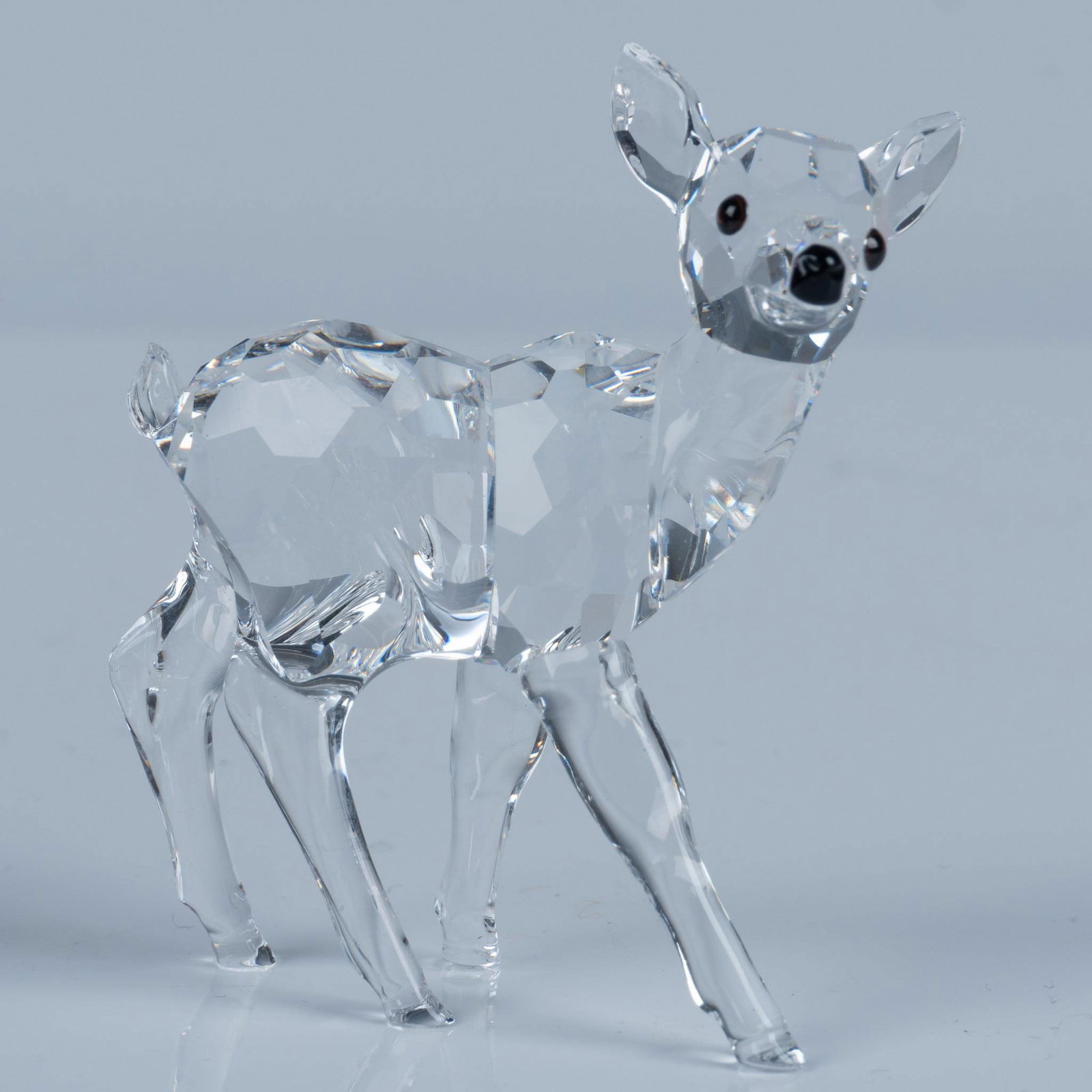 Swarovski Crystal Figurine, Fawn: A dazzling faceted figure of a cute deer with a black nose and amber-hued eyes. Swarovski acid mark. This item has its original box: 4.75"W x 4"H. Artist: Martin Zendron Issued: 1999-2006 Dimensions: 