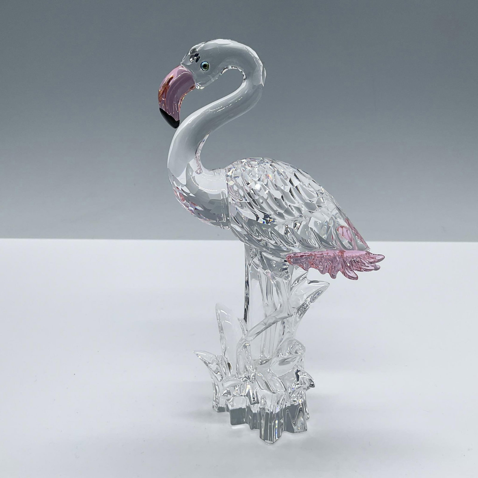 Swarovski Crystal Figurine, Flamingo: Part of the Feathered Beauties collection. Shines in clear faceted crystal with pink beak and tail. Swarovski acid backstamp. Includes the original box, dimensions: 7.75''L x 7.75''W x 5.75''H. Artist