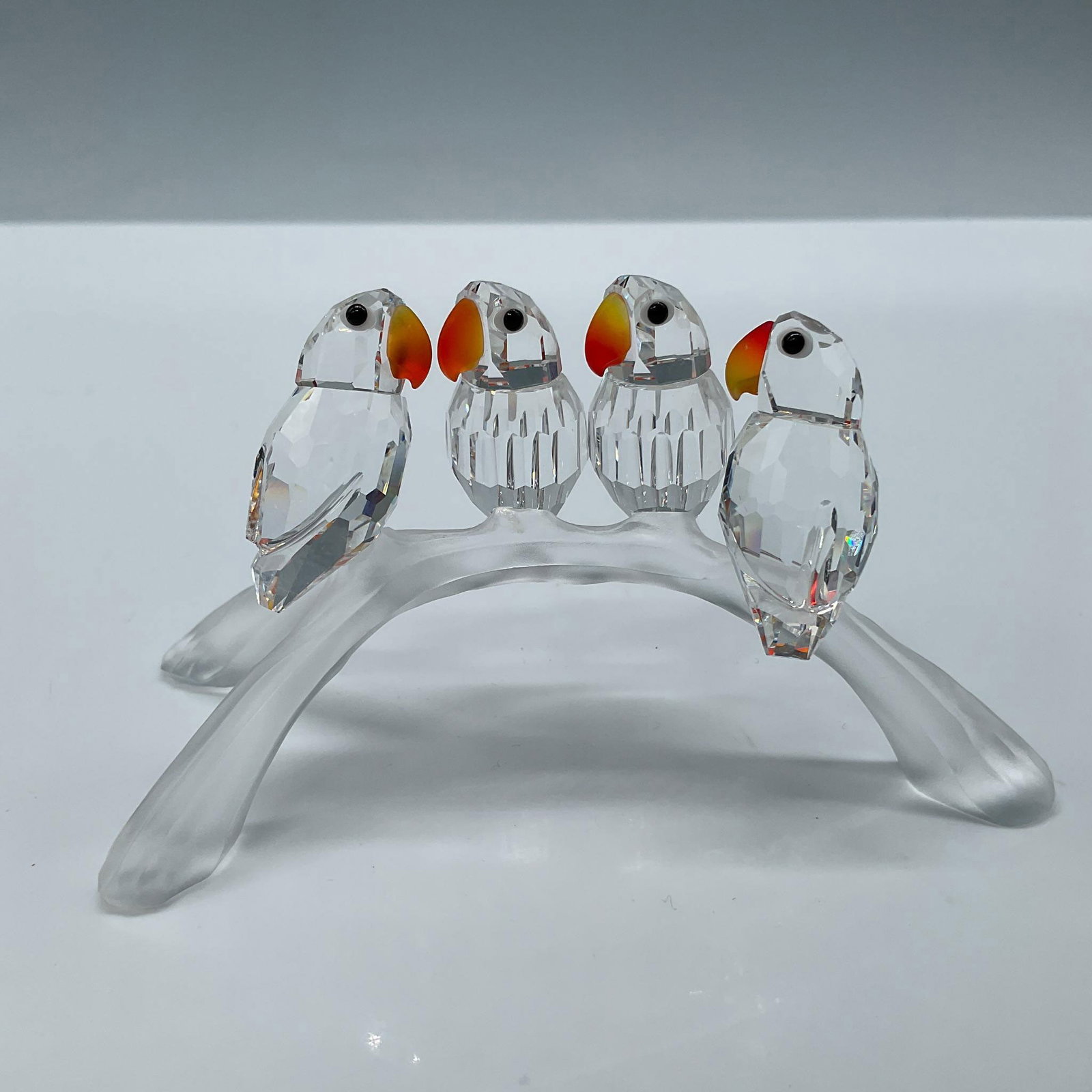 Swarovski Crystal Figurine, Baby Lovebirds: Adorable clear crystal birds with fire opal crystal beaks, perched on a frosted branch. Includes the original box, dimensions: 4.75''H x 6.25''dia. Swarovski etched backstamp. Artist: Adi Stocker Issu