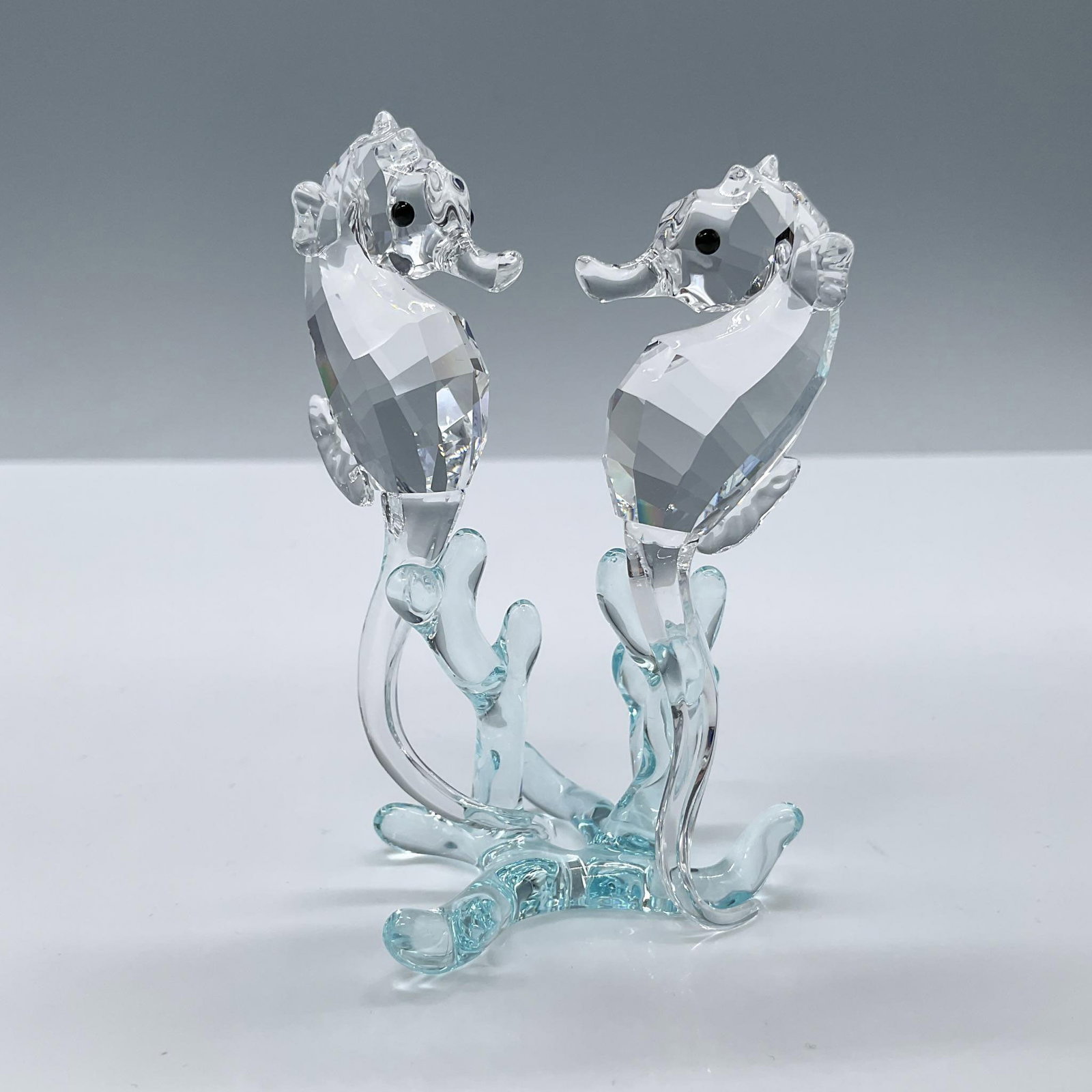 Swarovski Crystal Figurines, Seahorses: Beautiful faceted clear crystal duo of seahorses, set on a gradient light azure coral base. Swarovski backstamp. Includes the original box, dimensions: 4.75''L x 4.75''W x 3.25''H. Artist: Edith Mair 