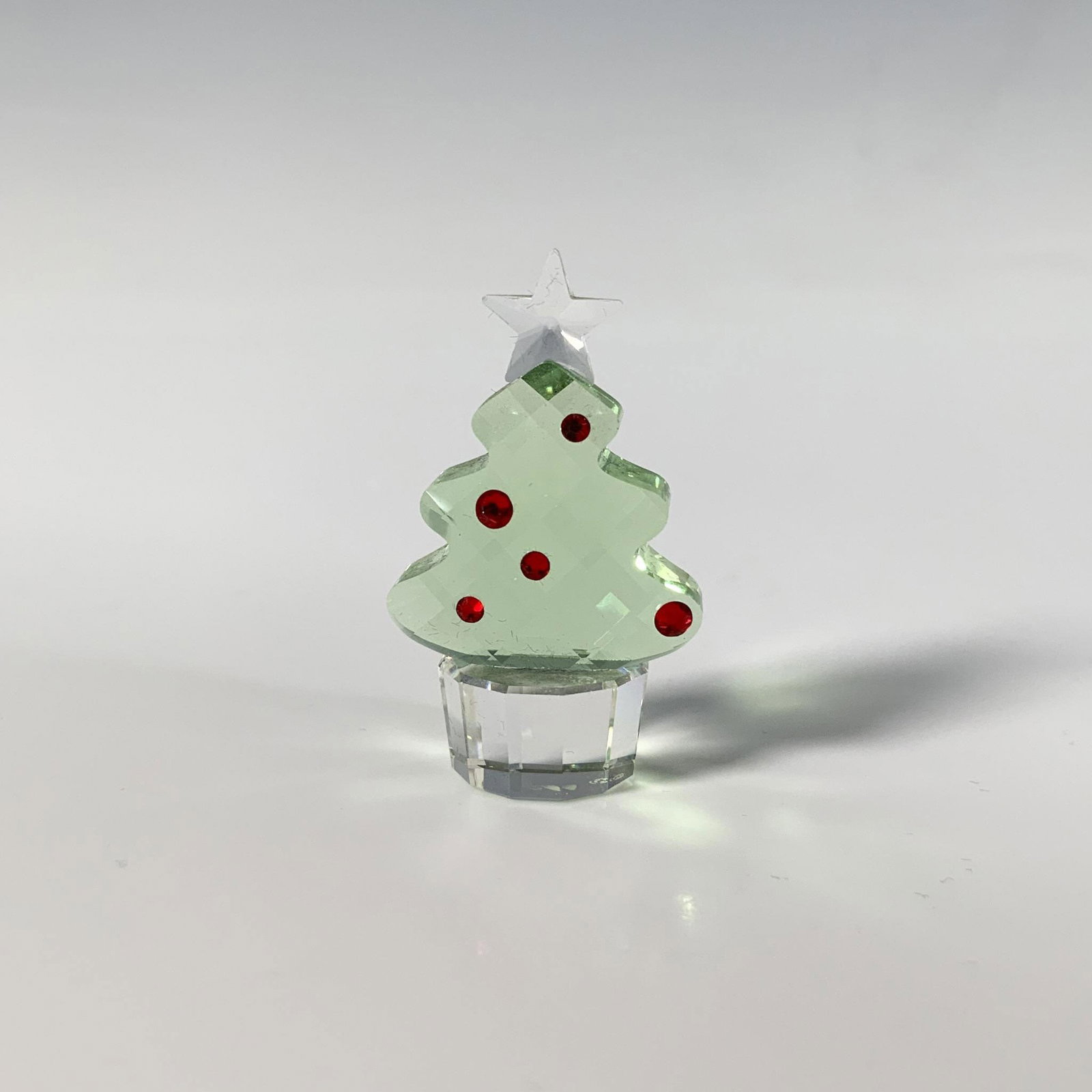 Swarovski Crystal Figurine, Felix The Christmas Tree: This delightful holiday decoration showcases a faceted crystal Christmas tree, accented with red gemstones. Swarovski marking. This item has its original box: 3"L x 3"W x 1.5"H. Artist: Eva Maria Ried