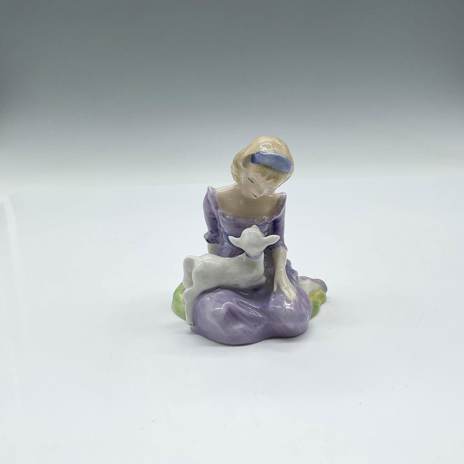 Mary Had A Little Lamb - HN2048 - Royal Doulton Figurine: Part of Nursery Rhymes Series One, figure sitting with her lamb colored in lavender. Royal Doulton backstamp. Artist: Peggy Davies Issued: 1949 - 1988 Dimensions: 3"L x 2.25"W x 3.5"H Manufacturer: Ro