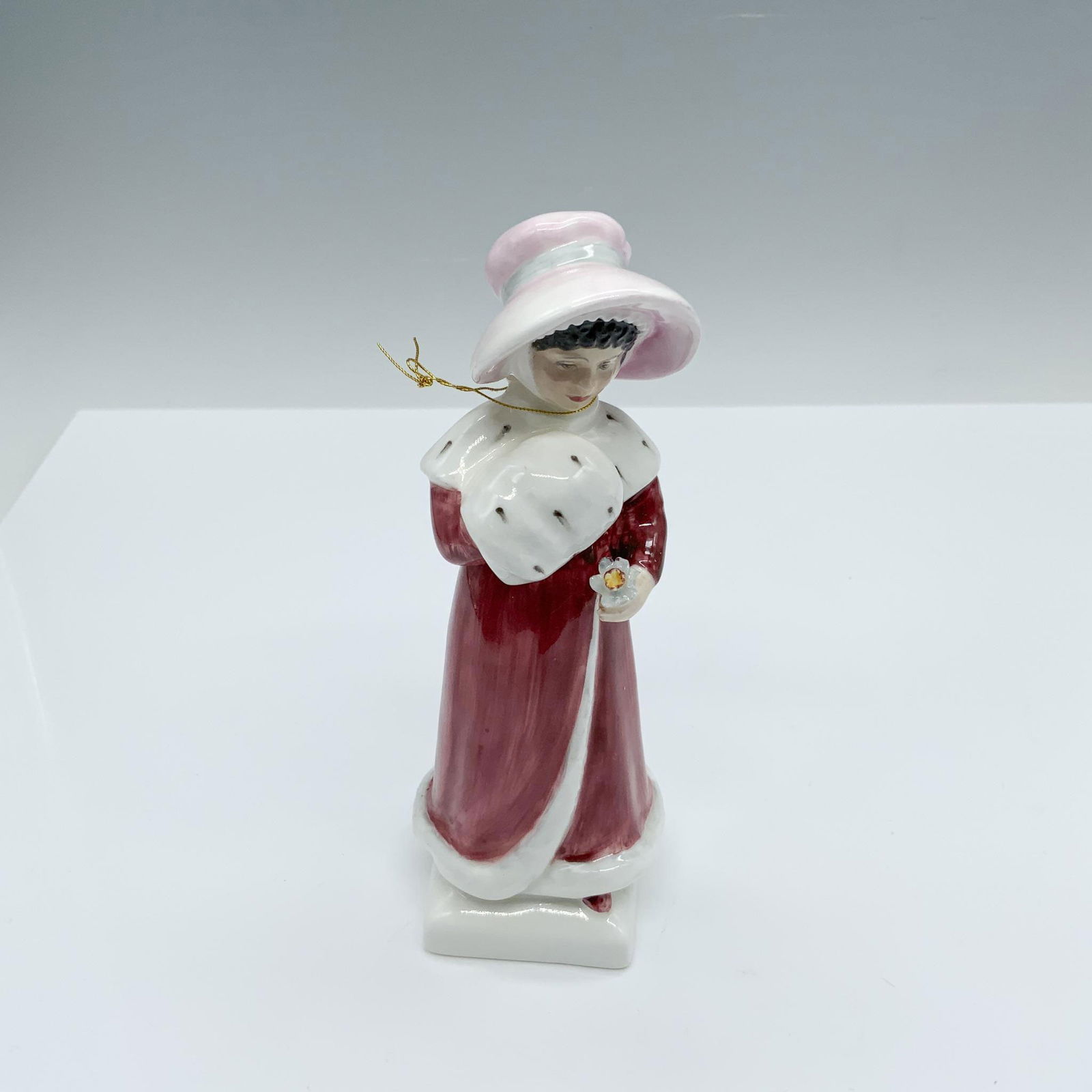 Sophie - HN2833 - Royal Doulton Figurine: This girl in a red and white fur coat holding a flower figure from the Kate Greenaway Collection is based of one of Kate's books named Under The Window which contains idyllic verses concerning childre