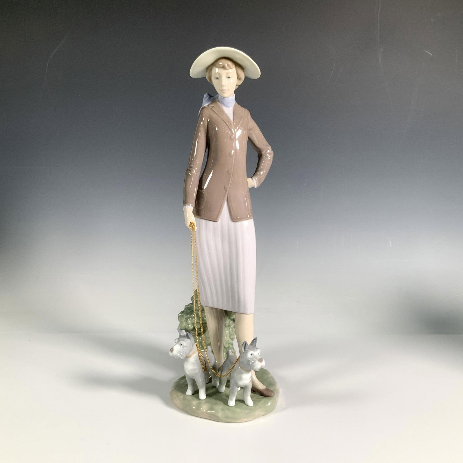 Walking The Dogs 1006760 - Lladro Porcelain Figurine: A lovely glossy figure of an elegantly dressed woman taking her two schnauzers on a stroll. Lladro backstamp. Artist: Regino Torrijos Issued: 2001-2004 Dimensions: 5"L x 6"W x 14"H Manufacturer: Lladr