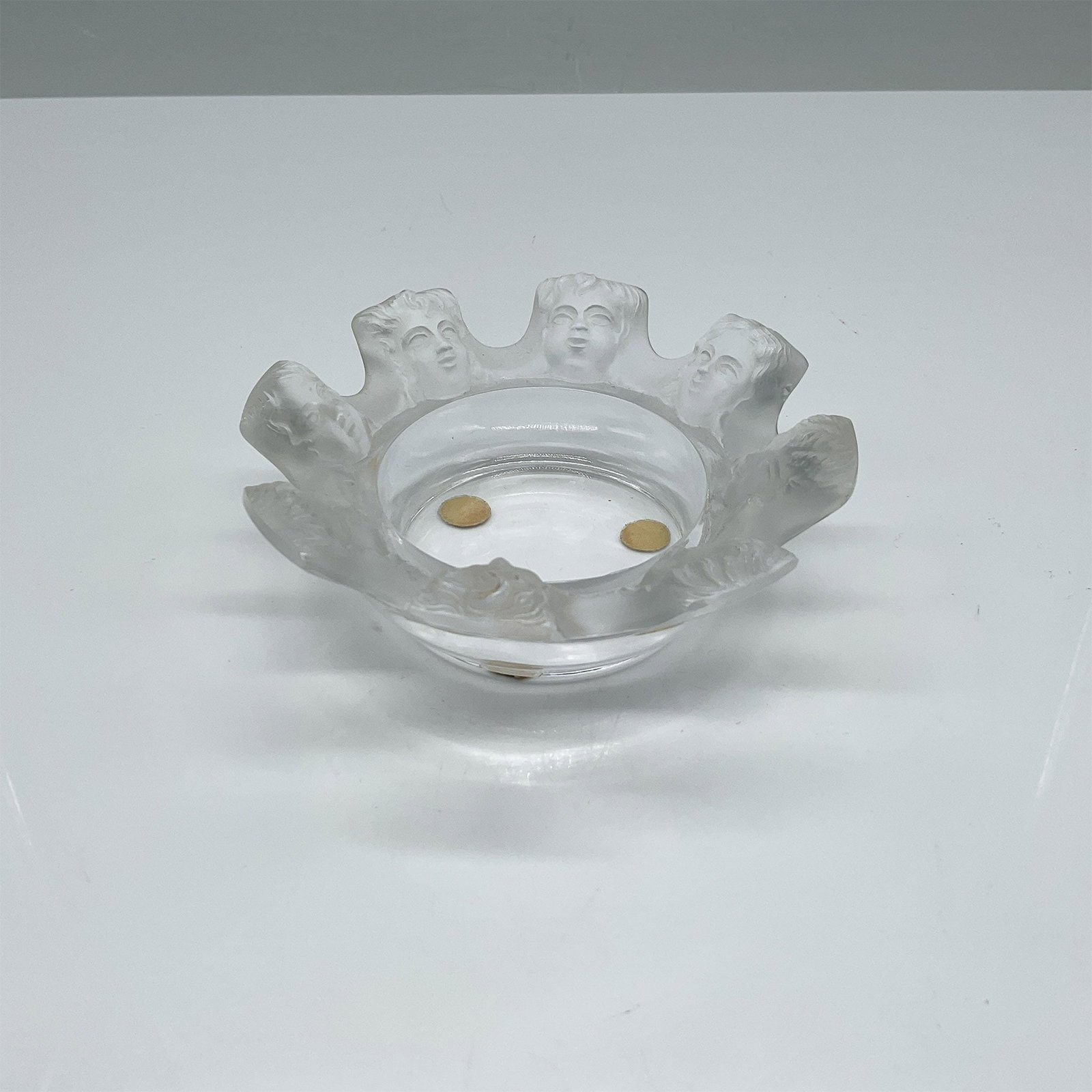 Lalique Crystal St. Nicholas Trinket Dish: This exquisite Lalique crystal trinket dish, known as the St. Nicholas design, features a ring of eight frosted cherub faces encircling the rim, beautifully contrasting with the clear crystal base. Ha
