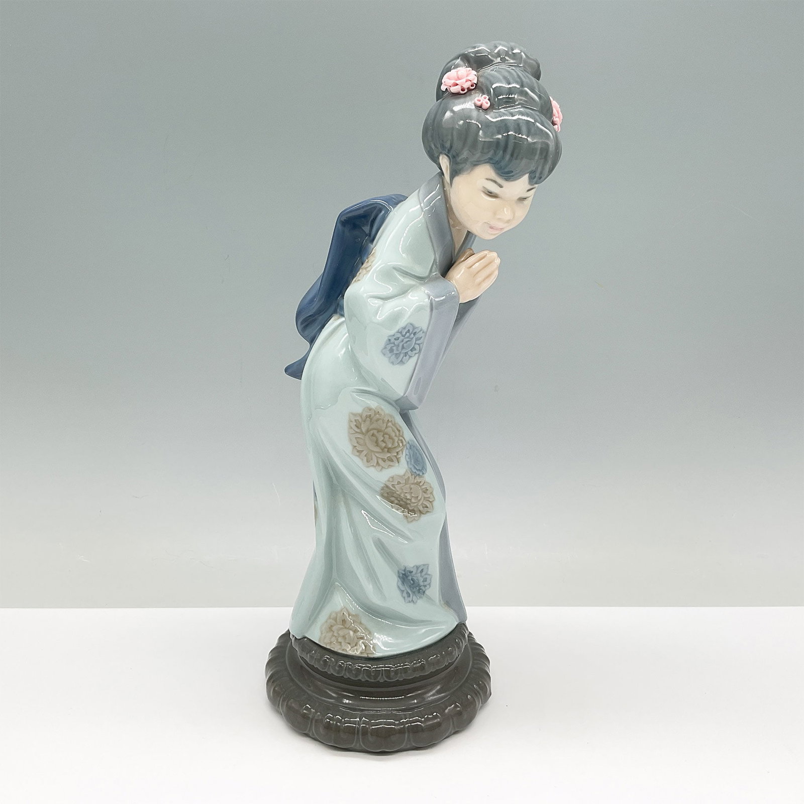 Lladro Porcelain Figurine, Sayonara 01004989: This is a Lladro porcelain figurine titled Sayonara, model number 01004989, depicting a young woman bowing gracefully in traditional Japanese attire. The figurine features a beautifully detailed kimon