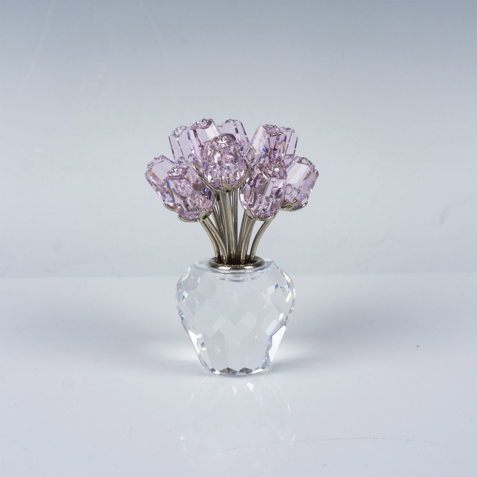 Swarovski "A Dozen Pink Roses" Crystal Figurine: The piece showcases a beautiful arrangement of twelve delicate pink crystal roses with finely detailed petals, arranged in a multifaceted clear crystal vase. The stems are accented with silver-toned m