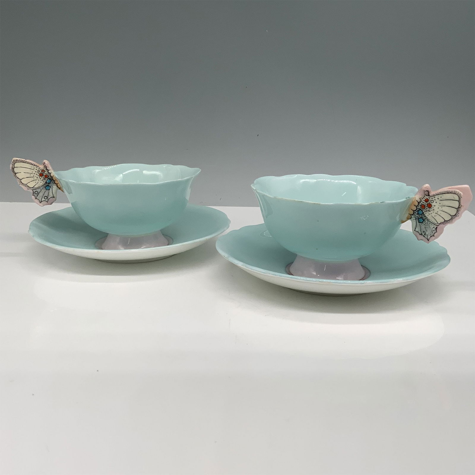 4pc Paragon Fine Bone China Butterfly Cup and Saucer Set: This charming set features two cups and two matching saucers from Paragon Fine Bone China, each adorned with a delicate butterfly handle design. The soft pastel blue coloring enhances the elegant form