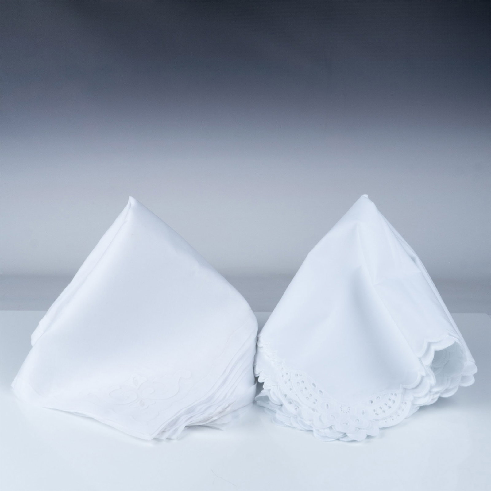 22pc White Embroidered and Scalloped Cloth Napkins: set of white cloth napkins featuring intricate embroidery and scalloped edges. The napkins showcase elegant designs, including floral cutwork patterns and decorative embroidery on some corners. Crafte