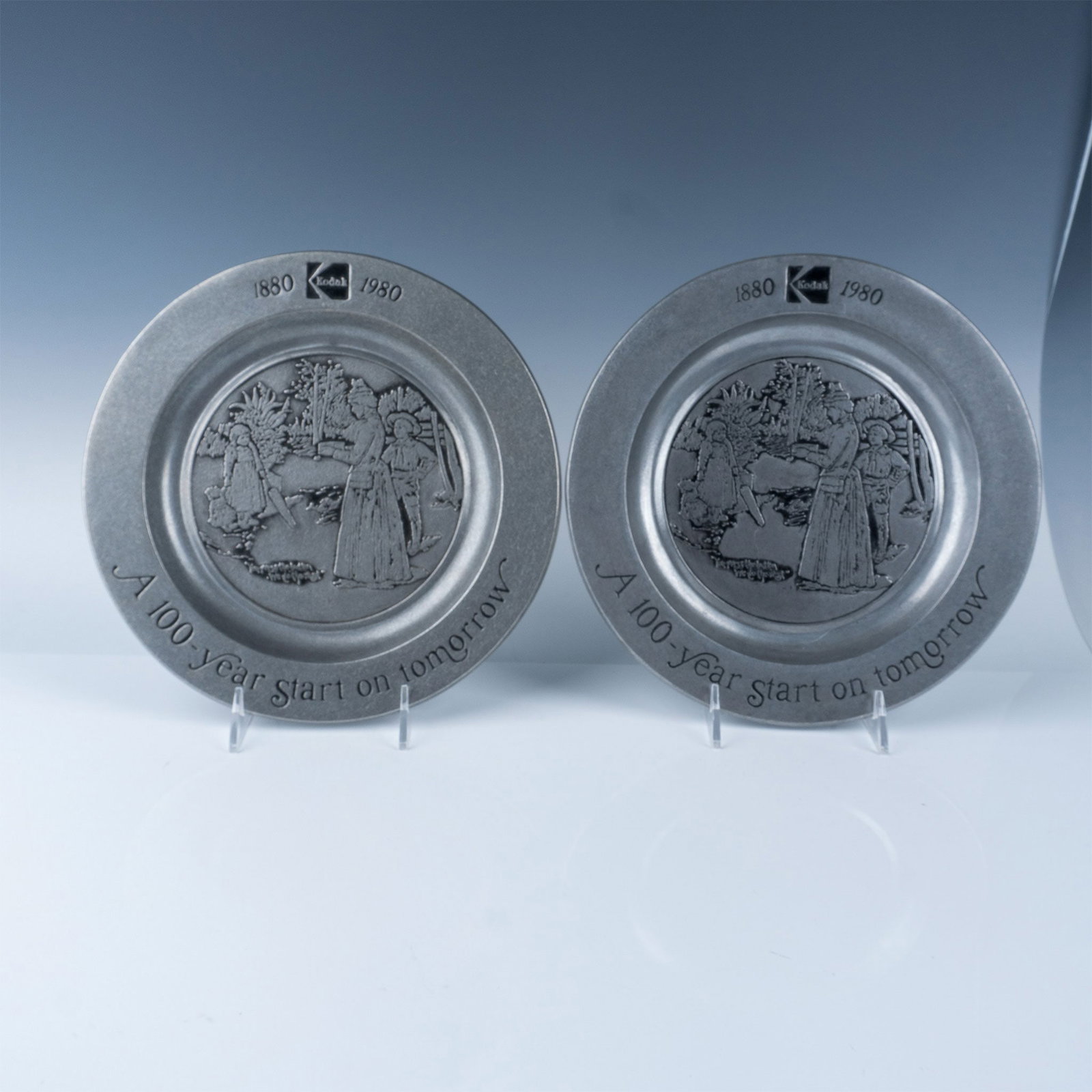 Pair of Kodak 100th Anniversary Pewter Plate (1880-1980): A beautifully crafted pewter plates commemorating Kodak’s centennial anniversary. The plate features an embossed design depicting a vintage Kodak moment, with the caption "You press the button, we d