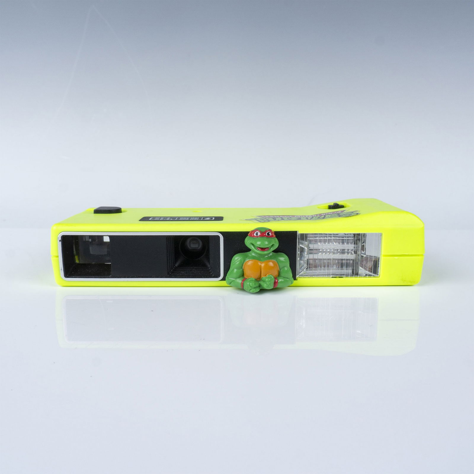 Mirage Studios Plastic Teenage Mutant Ninja Turtles Camera: Vintage Teenage Mutant Ninja Turtles plastic film camera featuring a Raphael character figurine. Manufactured by Mirage Studios, distributed by Recca Toys, and made in China. This bright neon yellow c