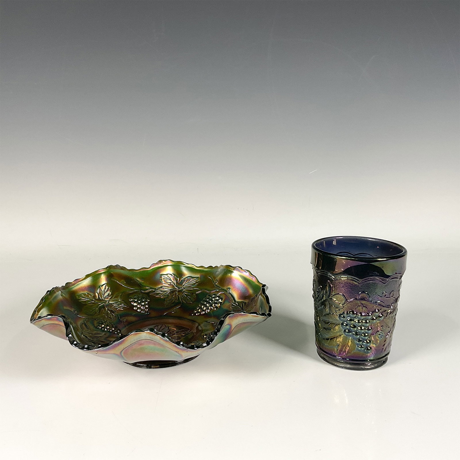 2pc Carnival Glass Bowl and a Cup: Iridescent bowl and cup set, beautifully adorned with elegant grape and leaf patterns, crafted from vibrant carnival glass. It features rainbow like sheen and combined with distinctive colors and intr