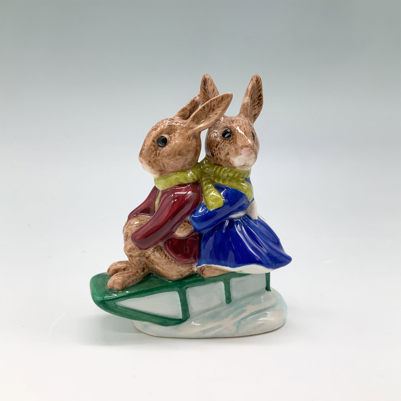 Royal Doulton Bunnykins Figurine, Billie and Buntie DB4: Royal Doulton fine bone china Bunnykins figurine titled Billie and Buntie, Sleigh Ride, depicting two rabbits sledding together. The piece features vibrant hand-painted details and includes the origin