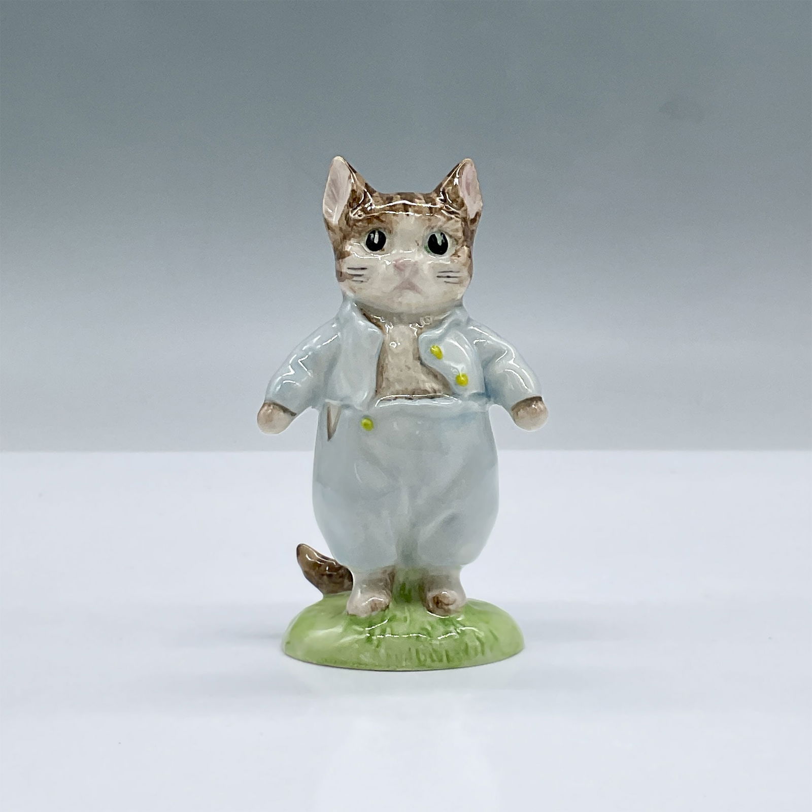 Royal Albert Beatrix Potter Figurine, Tom Kitten: Glossy porcelain. Features a kitten wearing blue on a patch of grass. Royal Albert Beatrix Potter backstamp. Issued: 1989 Dimensions: 2"L x 1.75"W x 3.75"H Country of Origin: England