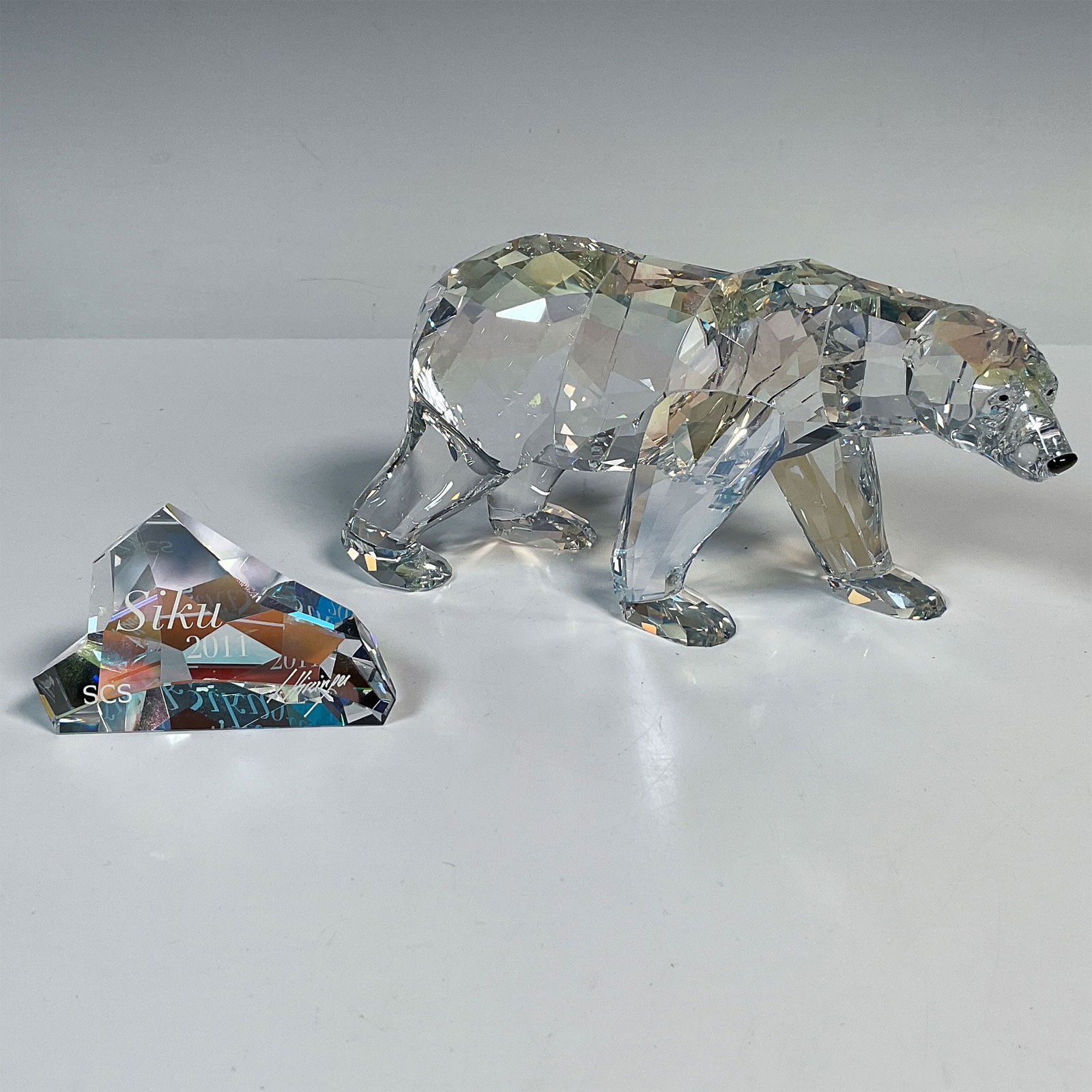 Swarovski Crystal Figurine, Siku Polar Bear + Plaque1053154: This 2011 annual edition polar bear is named Siku. He is crafted from moonlight colored crystal, with jet eyes and nose. Siku comes with an iceberg shaped plaque engraved with Siku 2011 and the design