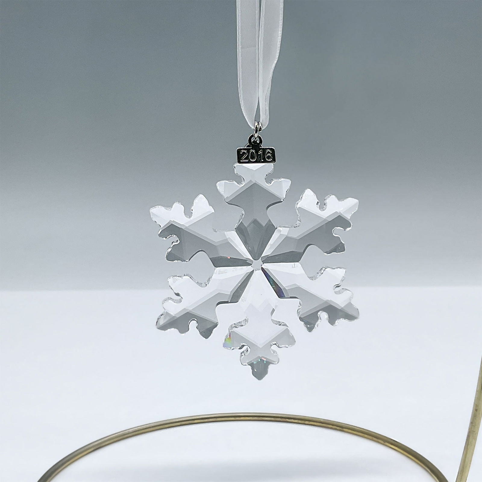 Swarovski Crystal Figurine, 2016 Christmas Ornament: A stunning sparkling clear crystal snowflake ornament, featuring a metal tag with the year of issue on a white ribbon. Swarovski engraving. 5180210. Artist: Verena Castelein Issued: 2016 Dimensions: 2