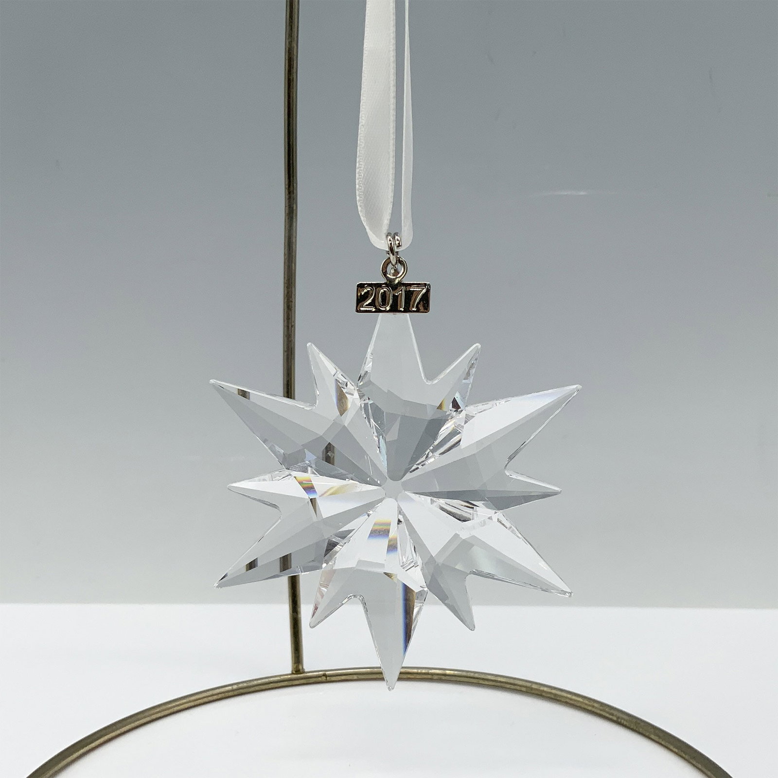 Swarovski Crystal 2017 Christmas Ornament: Continuing Swarovski tradition of Annual Edition ornaments, this stunning crystal star features a metal tag engraved with 2017 as it hangs on a white satin ribbon. Swarovski backstamp 5257589. Artist: