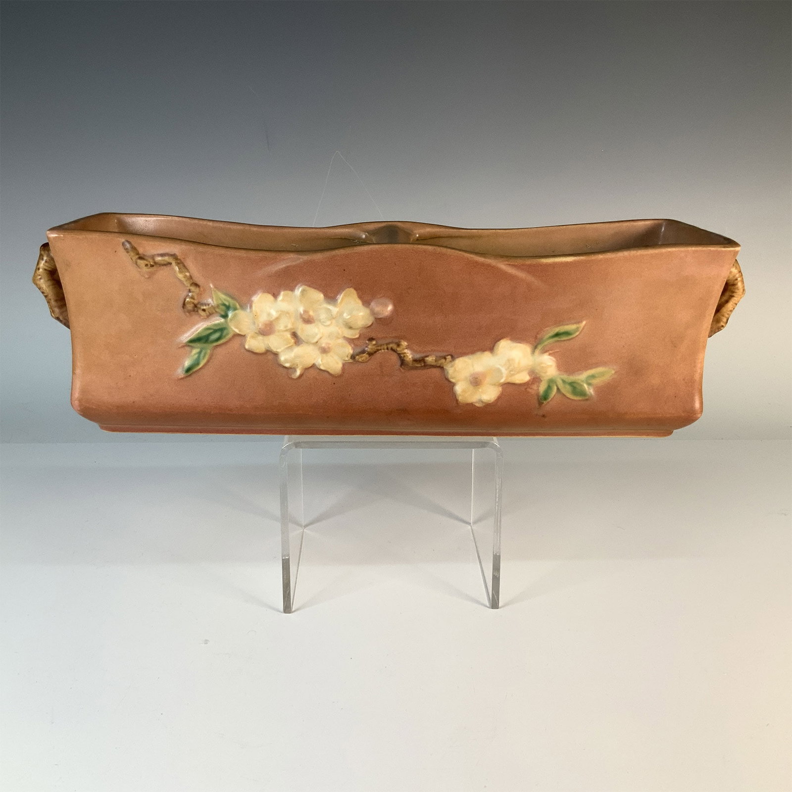 Roseville Pottery Planter, Apple Blossom Pattern: This vintage Roseville pottery planter showcases the charming Apple Blossom pattern, characterized by delicate floral designs on a warm brown background. Produced circa 1940s, the piece highlights Ros
