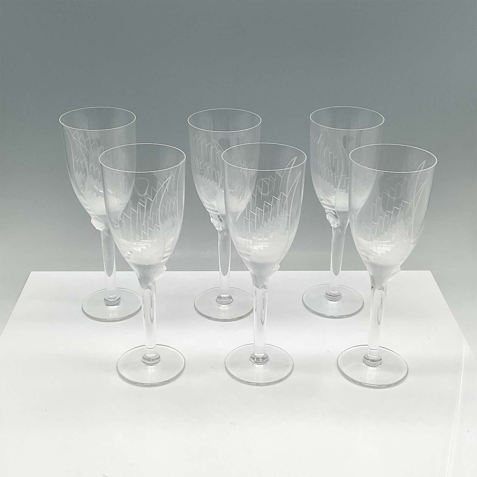 6pc Lalique Crystal Angel Wine Glasses: A stunning set of six Lalique crystal wine glasses, each elegantly crafted with etched detailing on the bowls and showcasing the brand's signature frosted embellishments on the stems. Renowned for the