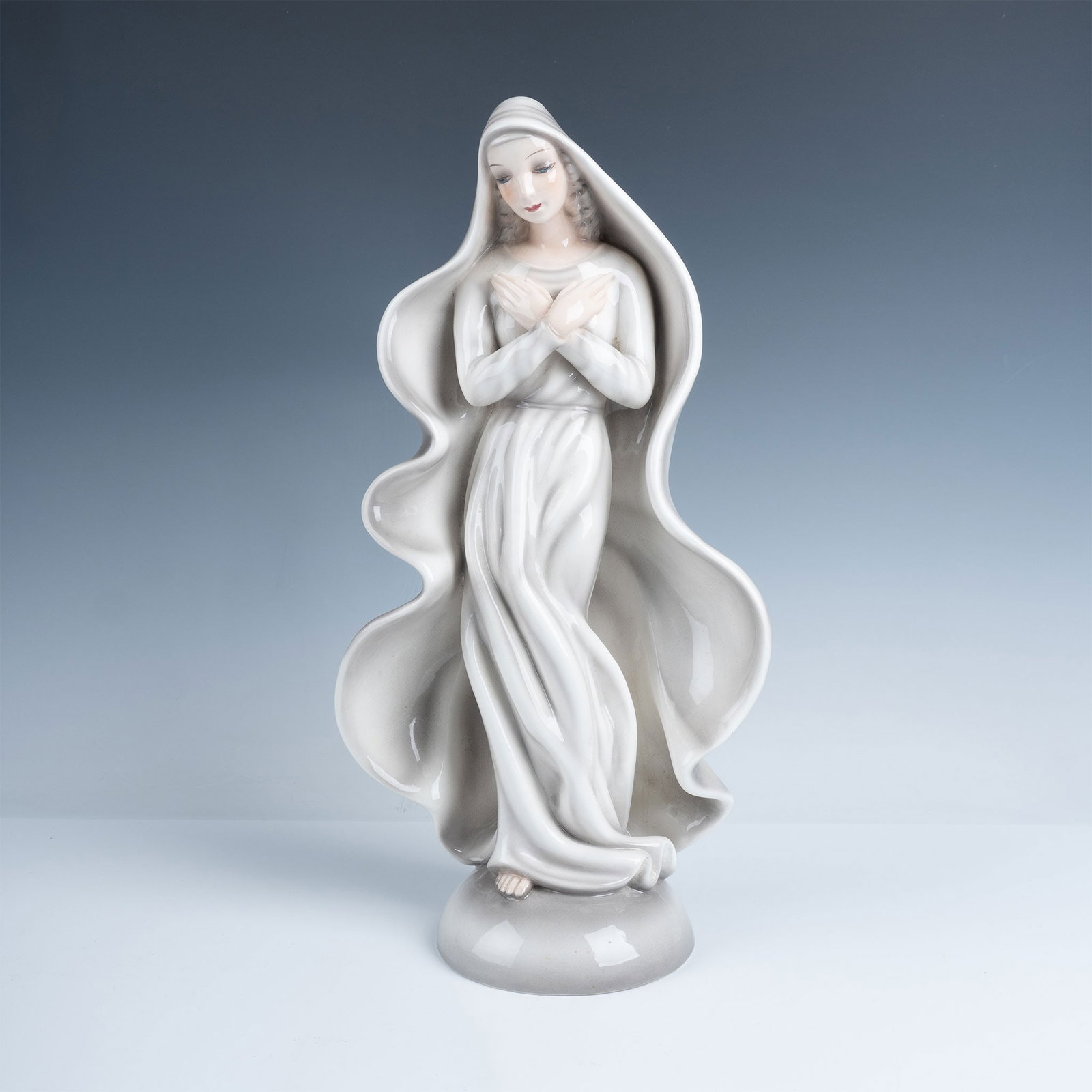 Goldscheider Porcelain Standing Madonna Statue: Serene sculpture of Madonna colored in cool gray and white. Signed on base Prischl. Goldscheider backstamp. 1862. Issued: 20th century Dimensions: 7.5"L x 4.5"W x 16"H Country of Origin: Austria