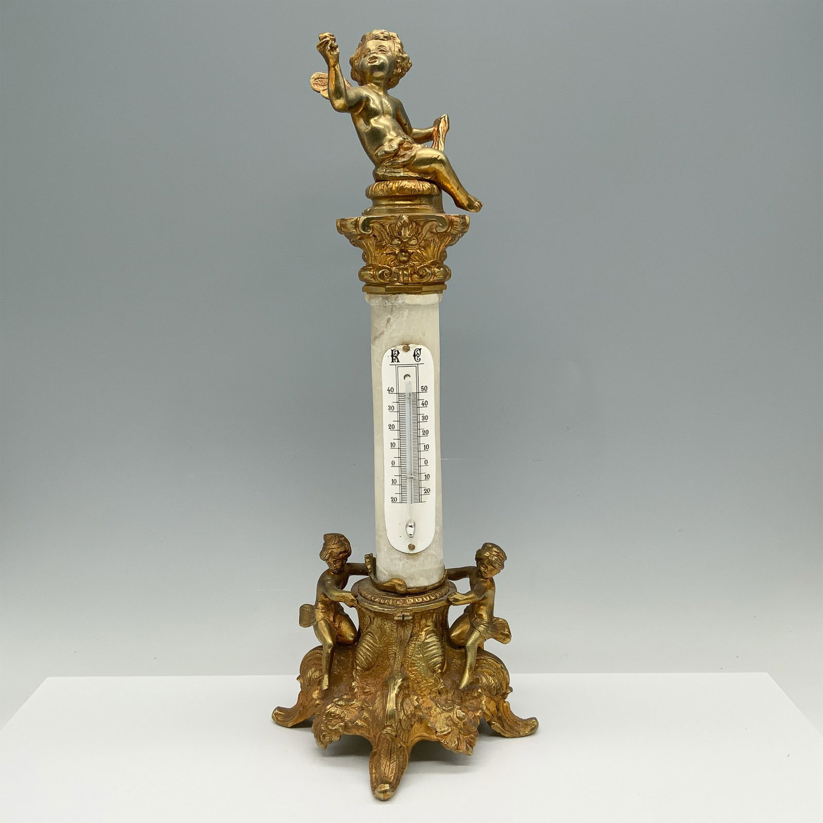 Neoclassical Bronze & Alabaster Cherub Thermometer: Adorable sculpture that doubles as a thermometer that is beautifully decorated with cherubs at its base and top. The sculpture is held up by curved feet and scroll designs whereas the body consists of