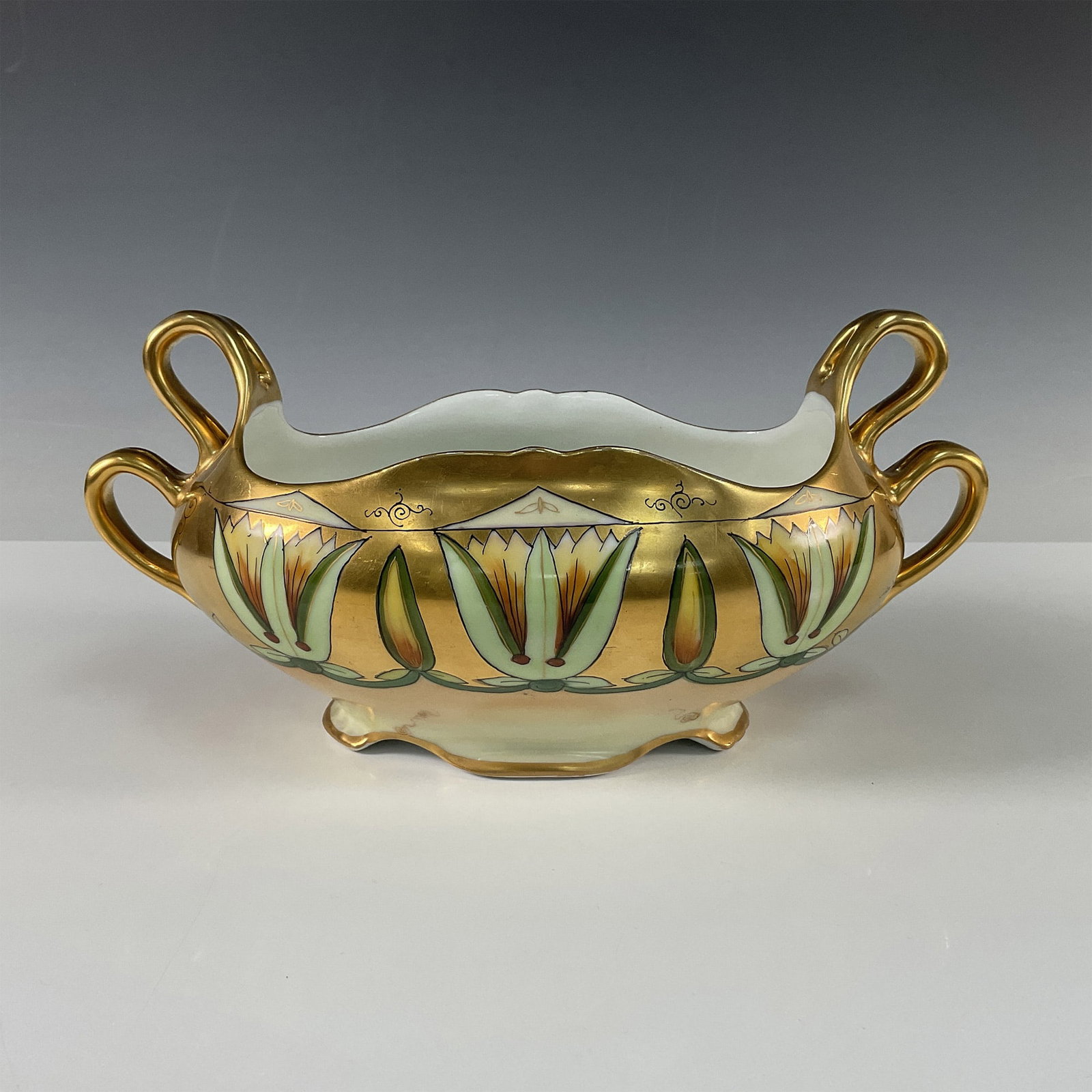 Pickard Bone China Egyptian Design Double Handle Bowl: An exquisite Pickard bone china double handle bowl featuring a hand painted Egyptian inspired motif. This stunning piece showcases vibrant lotus blossoms and geometric designs in rich hues of gold, gr