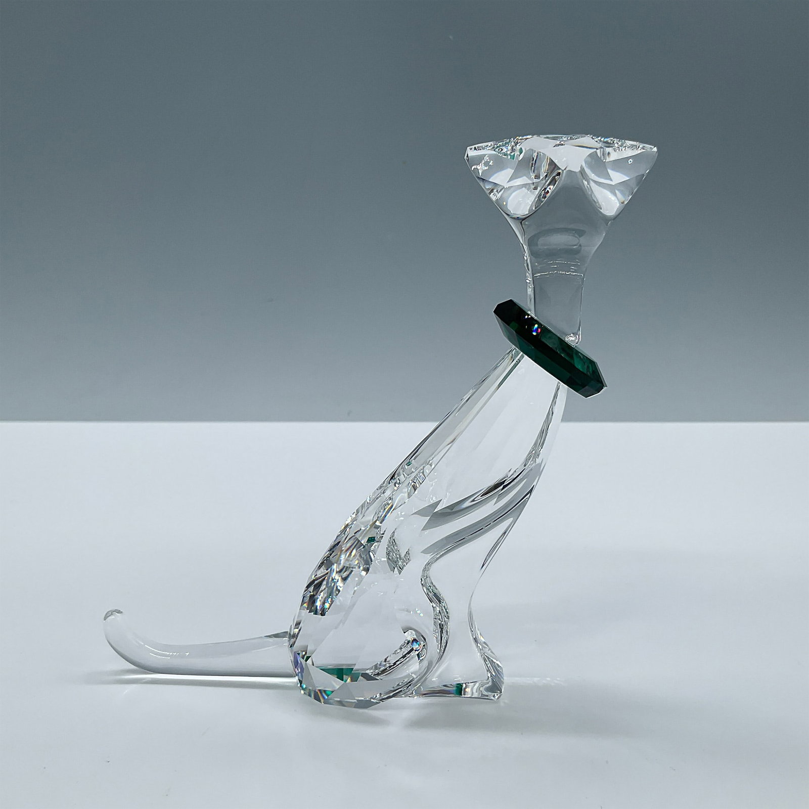 Swarovski Crystal Symbols Figurine, The Cat: Part of the Symbols Cat design. A clear feline with a green crystal collar. Swarovski etched backstamp. Box measures: 8''L x 7.25''W x 3.25''H. Artist: Adi Stocker Issued: 2002-2005 Dimensions: 4.5''L