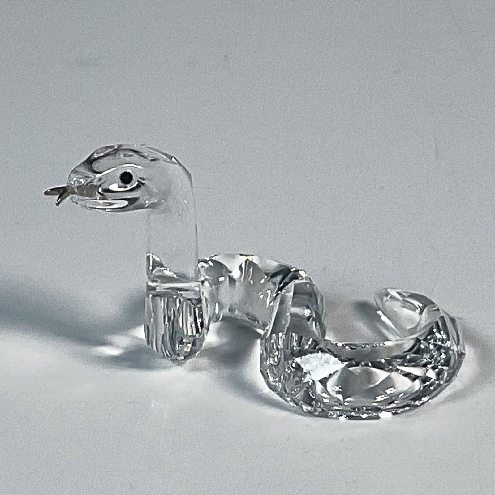 Swarovski Crystal Figurine, Zodiac Snake 625190: This adorable clear crystal snake was part of the Chinese Zodiacs collection. The snake has a faceted body with jet eyes and a metal tongue. Swarovski etched backstamp. This item has its original box.