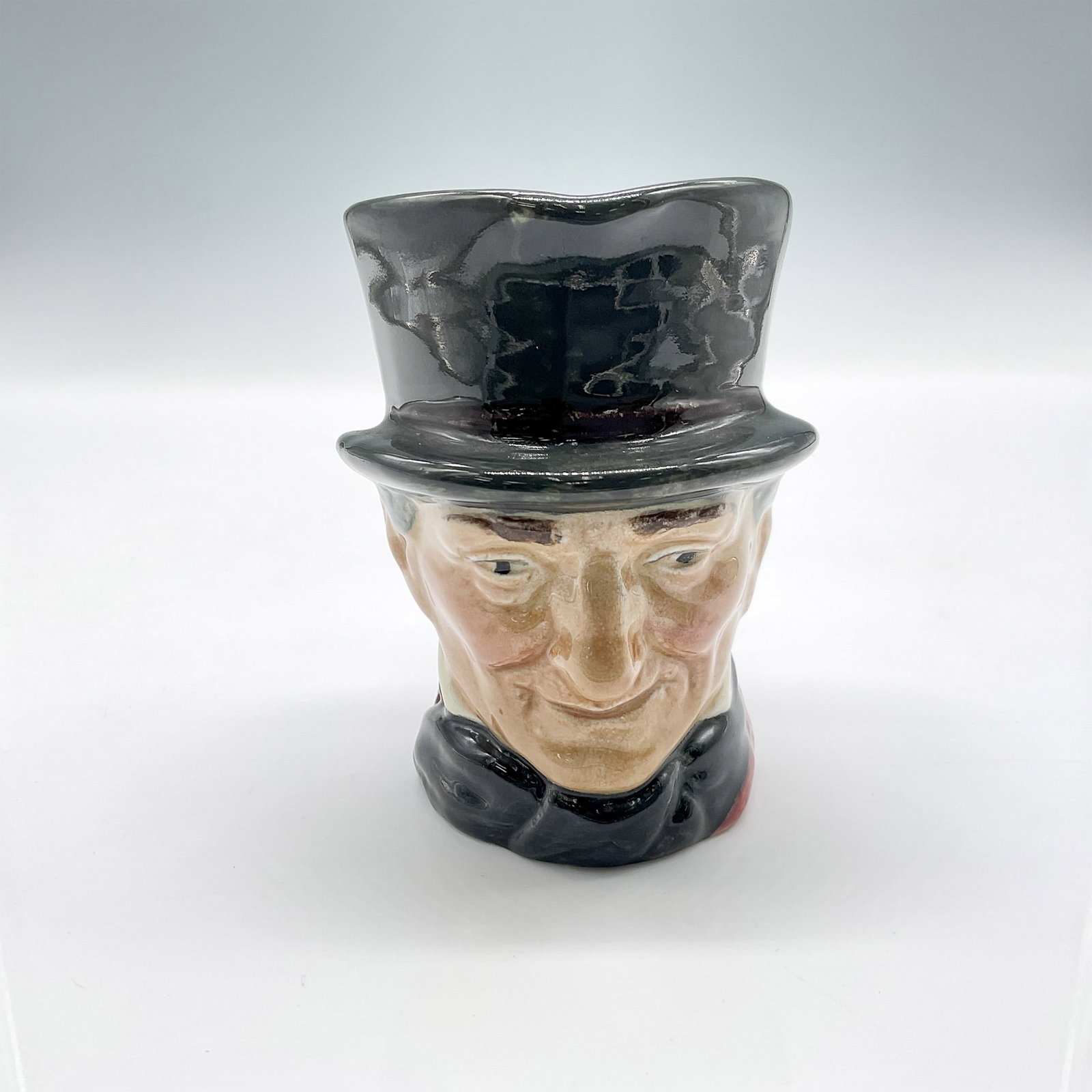 John Peel D5731 - Small - Royal Doulton Character Jug: Part of the Men of History series, dressed in dark grey hat, maroon coat, dark blue bow tie and grey riding crop. Royal Doulton backstamp. Artist: Harry Fenton Issued: 1937 - 1960 Dimensions: 4"L x 2.