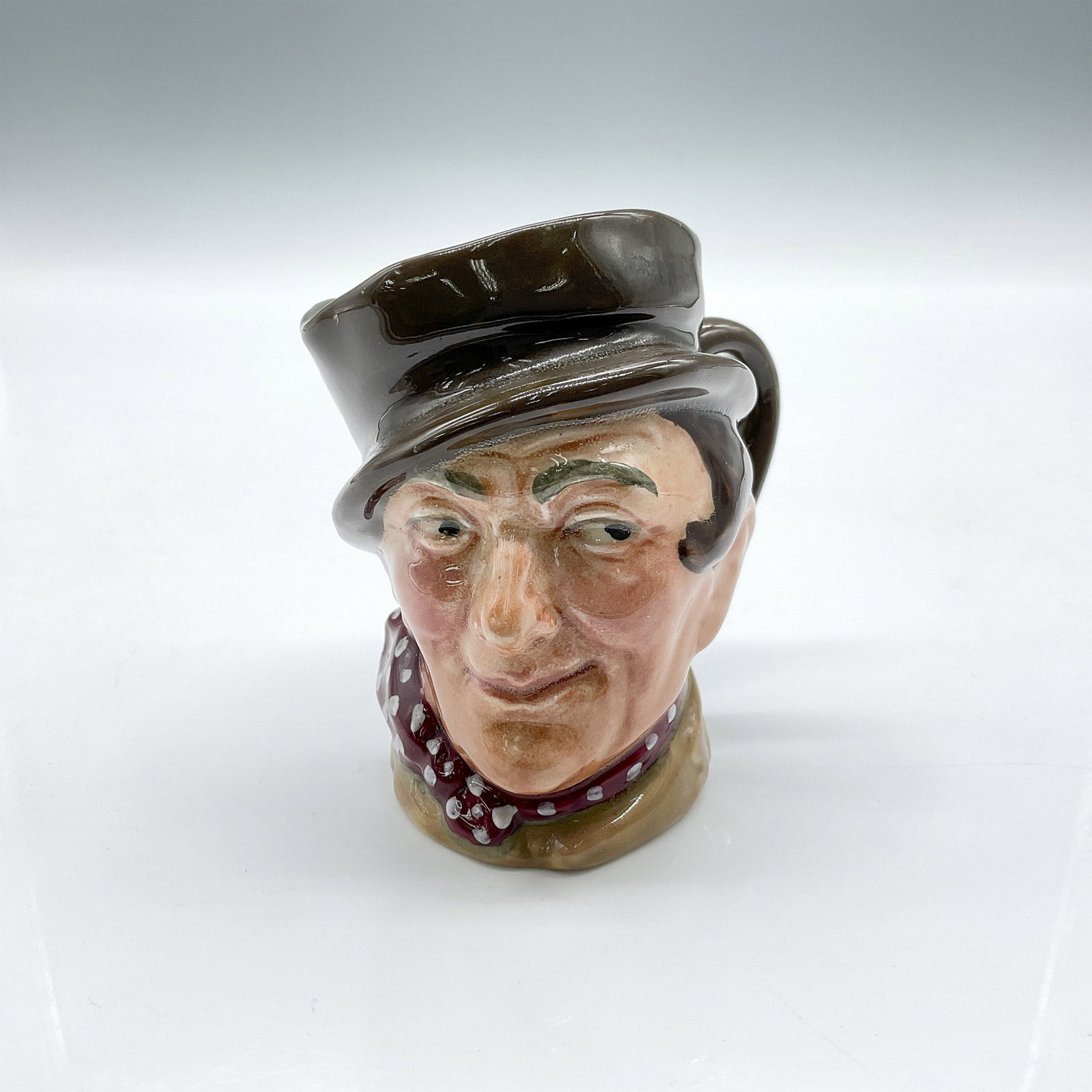 Sam Weller D5841 - Small - Royal Doulton Character Jug: Part of the Dickens characters, styled in dark brown hat, light brown coat, red kerchief with white spots. Royal Doulton backstamp. Artist: Leslie Harradine and Harry Fenton Issued: 1948 - 1960 Dimens
