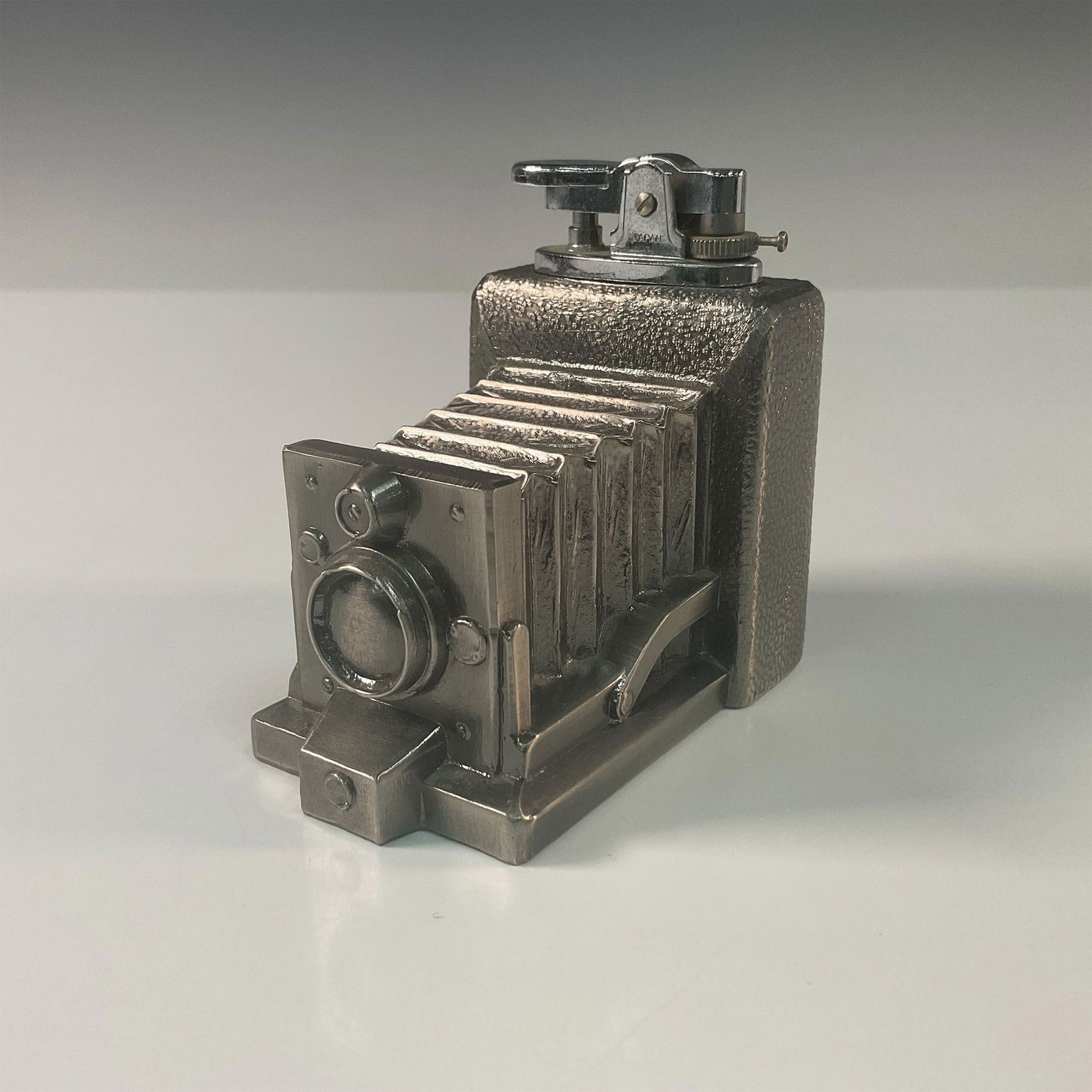 Vintage Japanese Metal Camera Theme Table Lighter: Unique Japanese silver-toned metal table lighter meticulously crafted in the form of an antique folding camera. This highly detailed piece replicates the intricate accordion-style bellows and textured