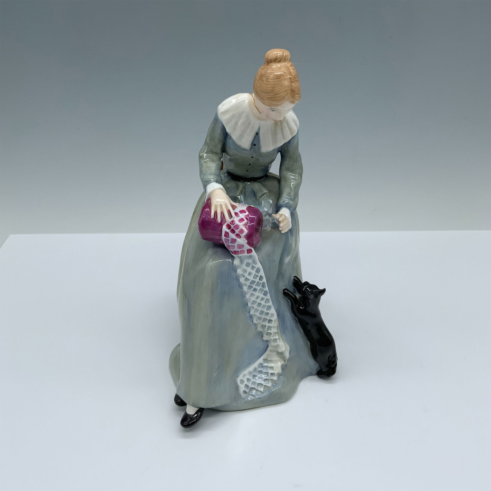 Royal Doulton Bone China Figurine, Dorothy HN3098: Handmade and hand decorated glossy figure of a woman in the process of fabricating a cloth as a cat seems interested in helping her unravel the yarn. Royal Doulton backstamp. Artist: Pauline Parsons I
