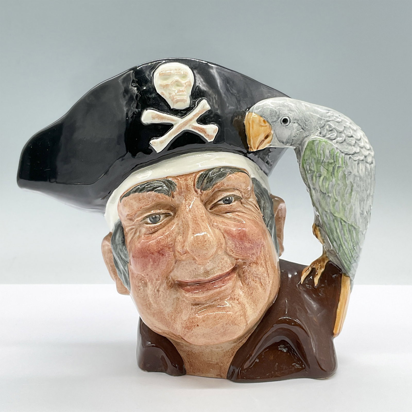 Long John Silver D6335 - Large - Royal Doulton Character Jug: Maroon shirt, green and grey parrot. Royal Doulton backstamp. Artist: Max Henk Issued: 1952 - 1998 Dimensions: 8''L x 5.5''W x 6.5''H Country of Origin: England